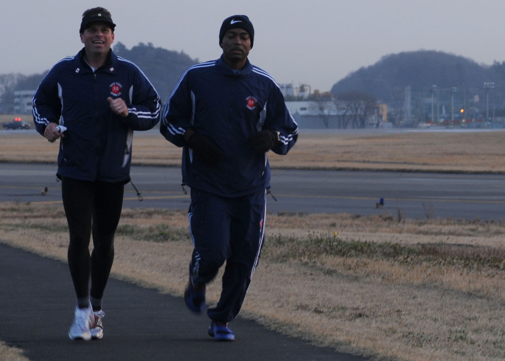YOKOTA AIR BASE, Japan -- Jeffrey Dickerhoof, Yokota Striders Running Club president, (left) and Senior Master Sgt. Artie Sanders, 374th Communications Squadron, run around the base's north perimeter March 17 during an early-morning workout session. Club members train three days a week and once on the weekend to prepare for races throughout Japan. (U.S. Air Force photo/Airman Devin Doskey)