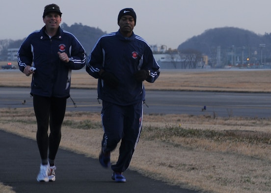 Jeffrey Dickerhoof, Yokota Striders Running Club president, (left) and Senior Master Sgt. Artie Sanders, 374th Communications Squadron, run around Yokota Air Base, Japan's north perimeter March 17 during an early-morning workout session. Club members train three days a week and once on the weekend to prepare for races throughout Japan. (U.S. Air Force photo/Airman Devin Doskey) 