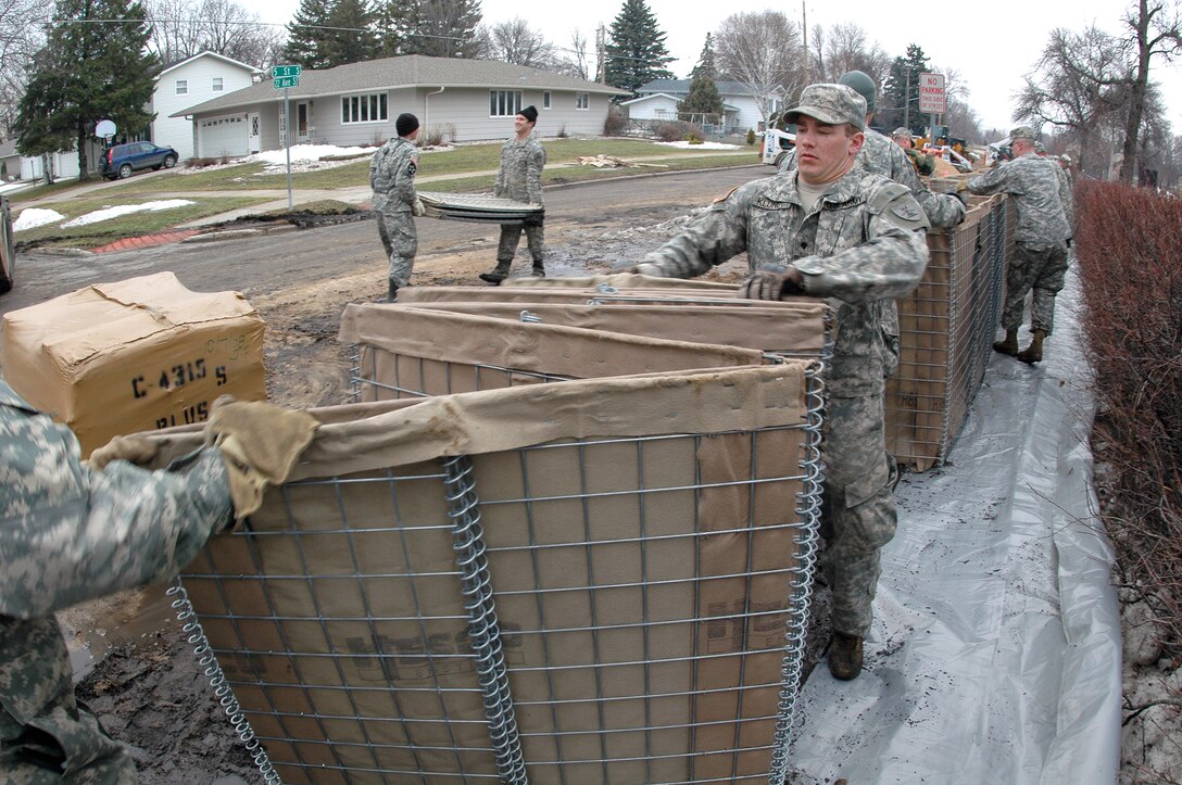 U.S. Army Spc. Joshua Klundt, right, pulls one end of a collapsible barrier in Fargo, N.D., March 24, 2009. Klundt is assigned to the 817th Engineer Company. Sections of collapsible barrier are being linked together and filled with sand to create to block the rising waters of the Red River.