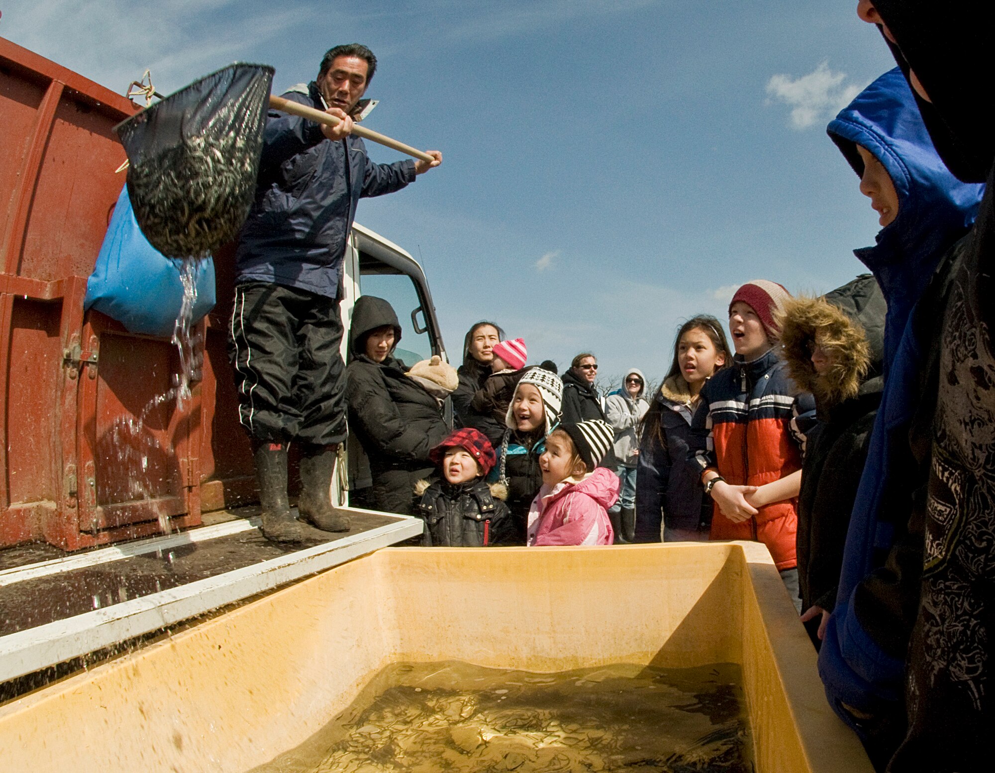 OIRASE TOWN, Japan -- Children watch a large amount of baby salmon being placed in a tub of water March 21, 2009. Children from the local community and the base helped release baby salmon into the river. (U.S. Air Force photo by Staff Sgt. Araceli Alarcon)