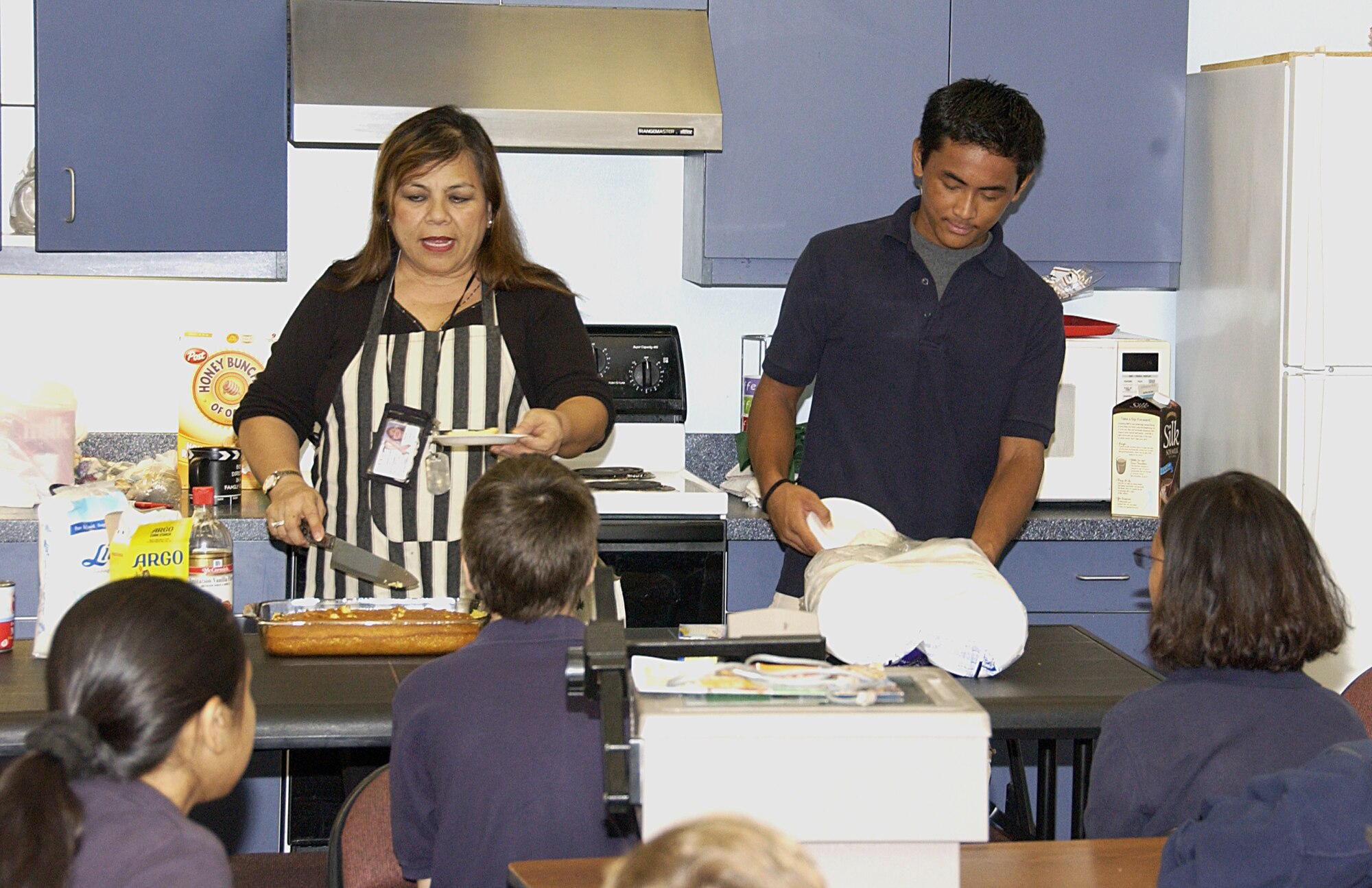 ANDERSEN AIR FORCE BASE, Guam -- Donovan Alger, an eighth grade student at Andersen Middle School, helps his Chamorro Culture Class teacher, Elizabeth Cruz put on a cooking demonstration for her sixth grade class March 19. Donovan was chosen as Andersen Middle School's Star Student due to his dedication to the classroom, his conduct within the classroom and his volunteer efforts. (U.S. Air Force photo by Airman Carissa Wolff)                             
