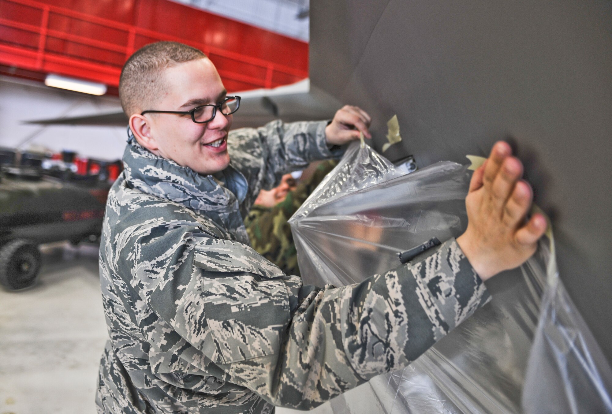 ELMENDORF AIR FORCE BASE, Alaska -- Airman 1st Class Paul Helms, 525th Aircraft Maintenance Unit, tapes plastic wrap on an F-22 March 26, 2009. Raptors and maintenance equipment from the 525th Fighter Squadron are sheltered inside a hangar due to the ongoing eruptions of Mount Redoubt. (U.S. Air Force photo by Senior Airman Matthew Owens)