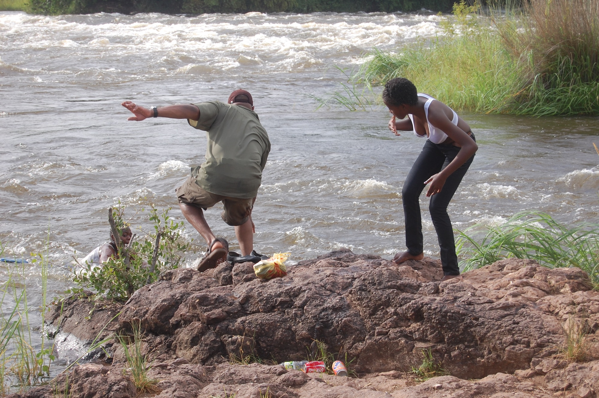 Lt. Col. Keith Andrews (left), an Air War College student, scrambles to rescue two girls in the water at the top of Victoria Falls in Zambia as another woman looks on. Colonel Andrews was visiting the tourist attraction in Africa as part of the school's Regional Cultural Studies class when the girls fell into the water. (Air Force photo by Col. Harold L. Wilson)