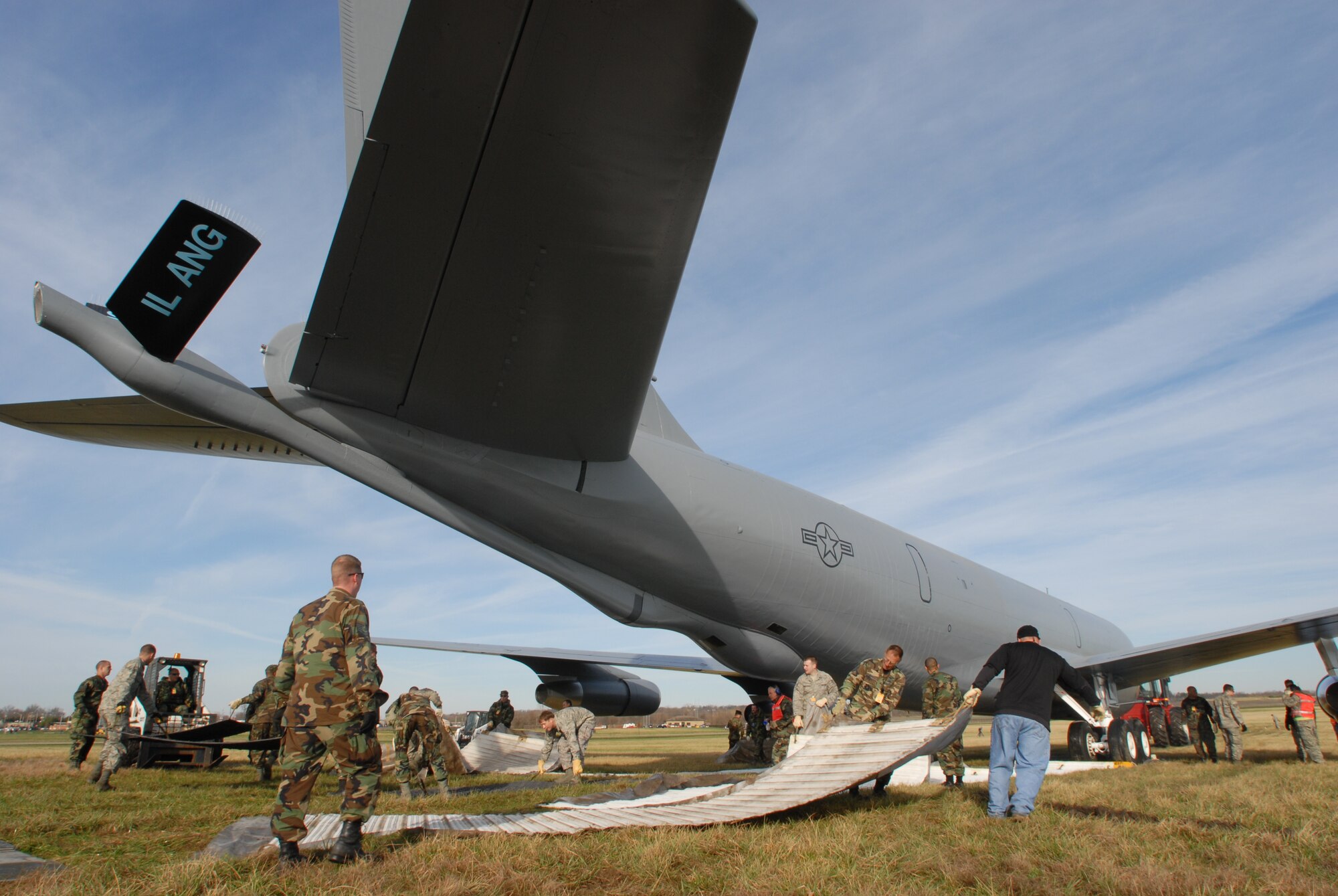 Members of the 126th Air Refueling Wing, 375th Airlift Wing and 182nd Airlift Wing work together to lay Mobi-Mats as a pathway for the movement of the last remaining KC-135E Stratotanker assigned to Scott Air Force Base, Illinois.  The aircraft will find its new, permanent home at Scott Field Heritage Park for the local community to enjoy.  (U.S. Air Force photo by Staff Sergeant Jessica Briney)
