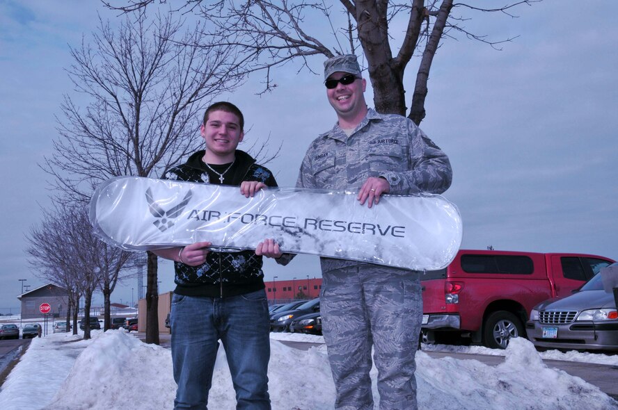 Tech. Sgt. Craig Dunbar, 934th Recruiter, presents a ?cool? Air Force Reserve snowboard to Jeremy Arsenault for his help in providing successful leads to recruiters and assitance in other recruiting programs. Mr. Arsenault is scheduled  to attend basic training in July and plans to train as a medical technician. (Air Force Photo/Tech. Sgt. Bob Sommer)
