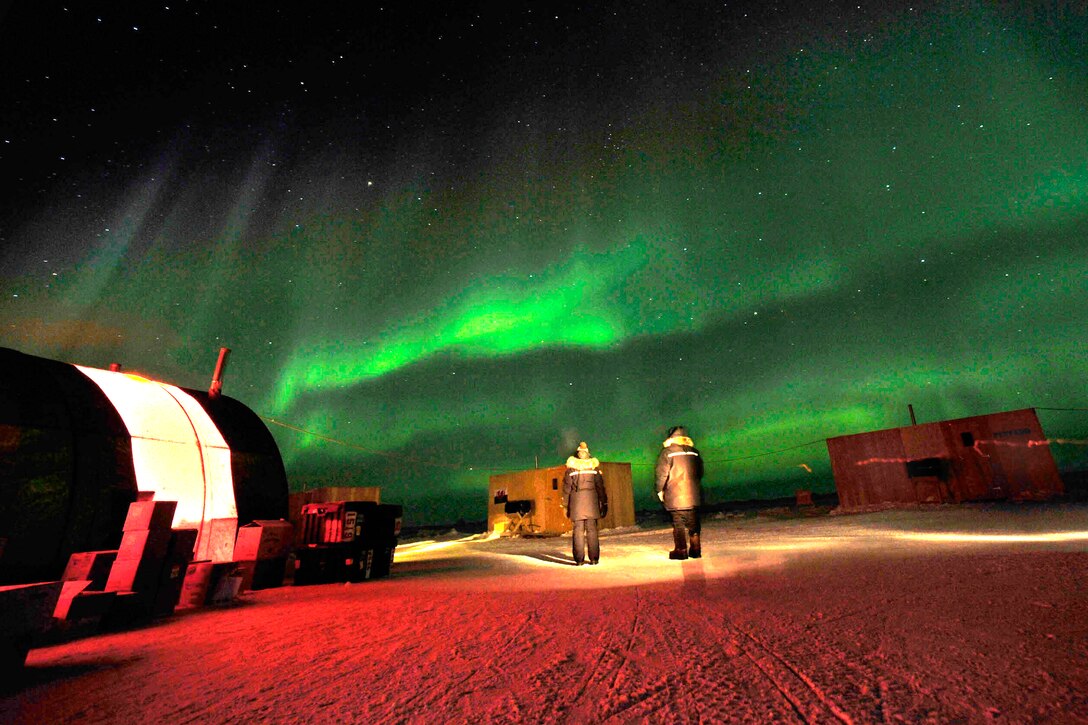 Personnel from the Applied Physics Lab Ice Station watch the aurora borealis light up the night sky over a temporary base camp set up on Arctic Ocean ice near Prudhoe Bay, Alaska, March 21, 2009.