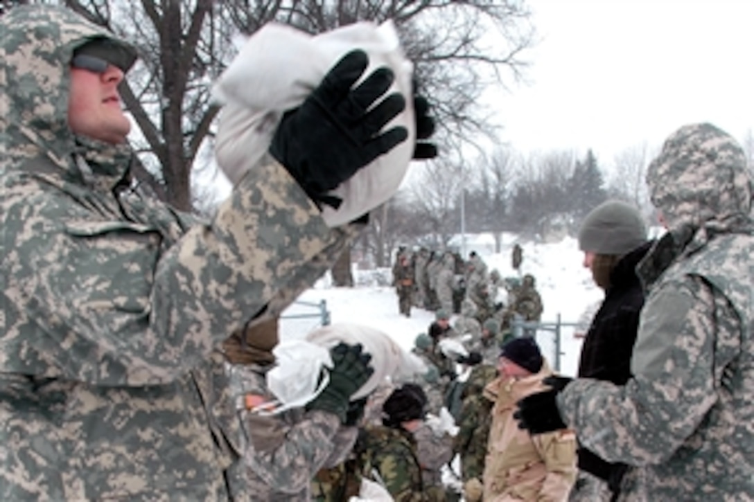 North Dakota National Guard soldiers and airmen form a human chain as they pass sandbags along to build sandbag dikes in Fargo, N.D., March 25, 2009. The soldiers and airmen are building the dikes to create barriers to block rising flood waters of the Red River along the North Dakota and Minnesota border. 