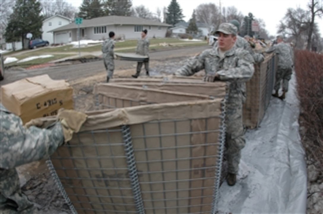 U.S. Army Spc. Joshua Klundt, 817th Engineer Company, pulls one end of a HESCO collapsible barrier in Fargo, N.D., on March 24, 2009.  Sections of collapsible barrier are being linked together and filled with sand to create a flood barrier to block the rising waters of the Red River.  