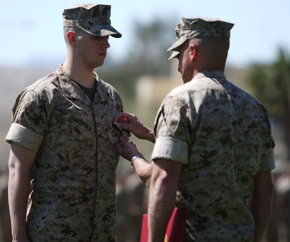 Lance Cpl. Brady A. Gustafson, a machine gunner with Golf Company, 2nd Battalion, 7th Marine Regiment, receives the Navy Cross, the second highest award in the military, from his current commanding officer, Lt. Col. John M. Reed at a ceremony held at Lance Cpl. Torrey Grey Field March 27.