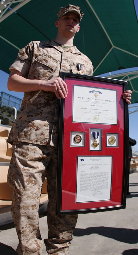 Cpl. Brady Gustafson, a machine gunner with Golf Company, 2nd Battalion, 7th Marine Regiment, proudly displays a framed copy of his Navy Cross citation and medal after a ceremony where he was awarded the Navy Cross and a meritorious promotion to corporal at Lance Cpl. Torrey Grey Field March 27.