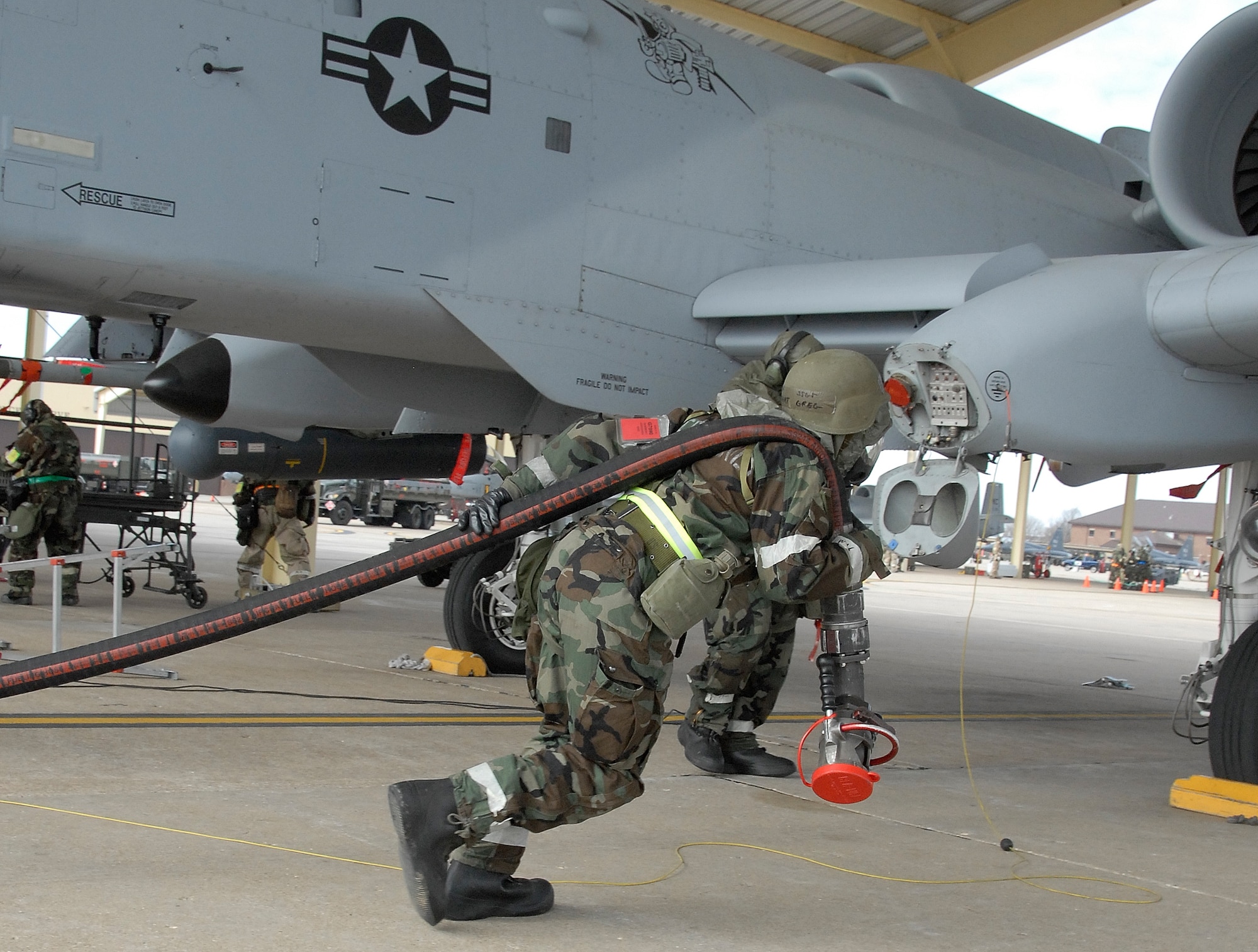 Dressed in chemical warfare protective clothing while participating in an operational readiness exercise, Staff Sgt. Greg Guebert, a 442nd Logistics Readiness Squadron fuels specialist, unwinds a refueling hose to be attached to an 442nd Fighter Wing A-10 Thunderbolt II as crew chief, Tech. Sgt. Pete Melby, 442nd Aircraft Maintenance Squadron, waits by the aircraft. The 442nd FW is an Air Force Reserve Command unit based at Whiteman Air Force Base, Mo. (US Air Force photo/Master Sgt. Bill Huntington)