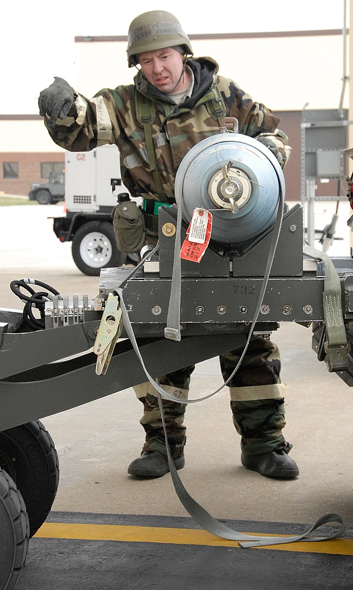 While participating in a simulated chemical warfare exercise, Master Sgt. Ken McKee, a 442nd Aircraft Maintenance Squadron weapons load crew member, signals to fellow crew member, Tech. Sgt. Randall Kennedy, as they move an inert training bomb to be secured to a 442nd Fighter Wing A-10 Thunderbolt II. The 442nd AMXS is part of the 442nd FW, an Air Force Reserve Command unit based at Whiteman Air Force Base, Mo., which used the exercise to train its members to be able to continue to operate in all warfare environments. (US Air Force photo/Master Sgt. Bill Huntington)