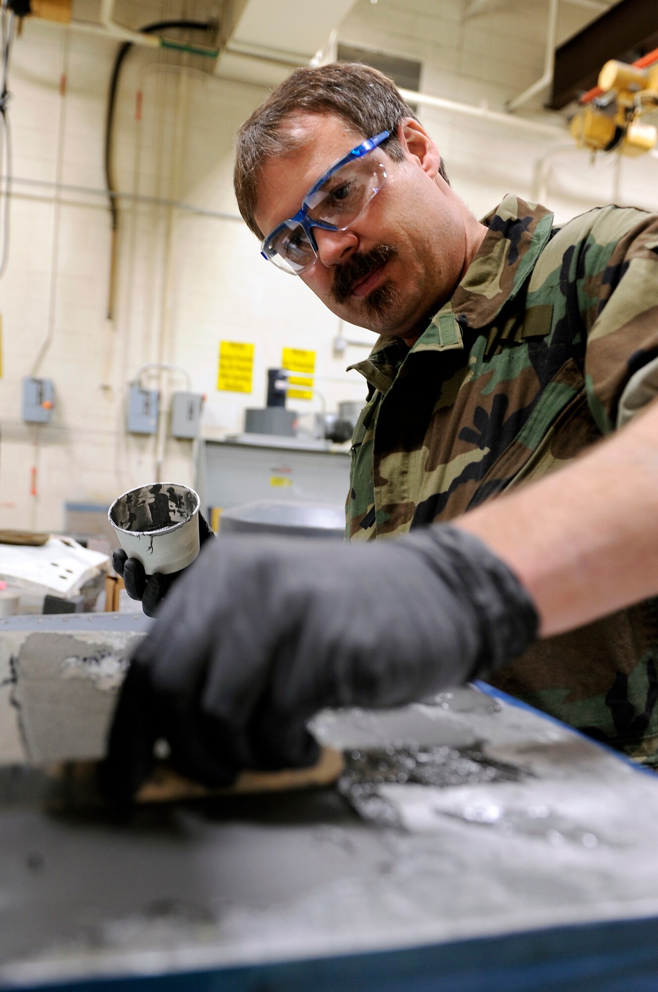 Shane Shaughnessy, 28th Maintenance Squadron structural technician, applies epoxy to a map case, March 27. The epoxy is used to bond a sheet of reinforcement metal to the map case. (U.S. Air Force photo/Senior Airman Marc I. Lane)
