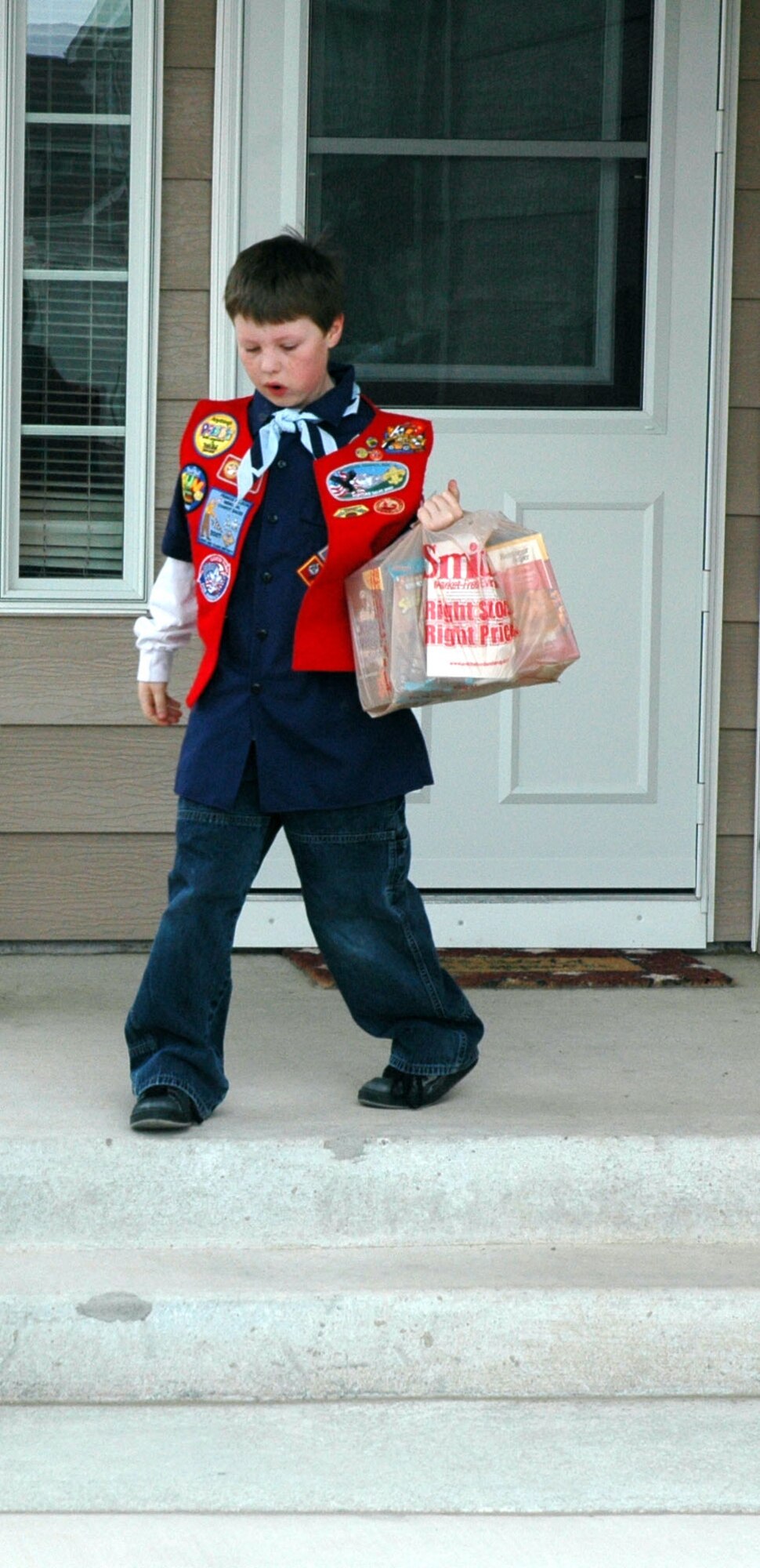 Drayke, 9, Cub Scout Pack 43 member, collects a bag of donated food from a doorstep in base housing. Each pack member will receive a patch for their participation in the food drive, which they can add to their uniform. Those interested in enrolling their children from grades K to 1st grade in the Cub Scouts can contact Tech. Sgt. John Cottle, cub master, at 731- 4622. (U.S. Air Force photo/Senior Airman Dillon White)