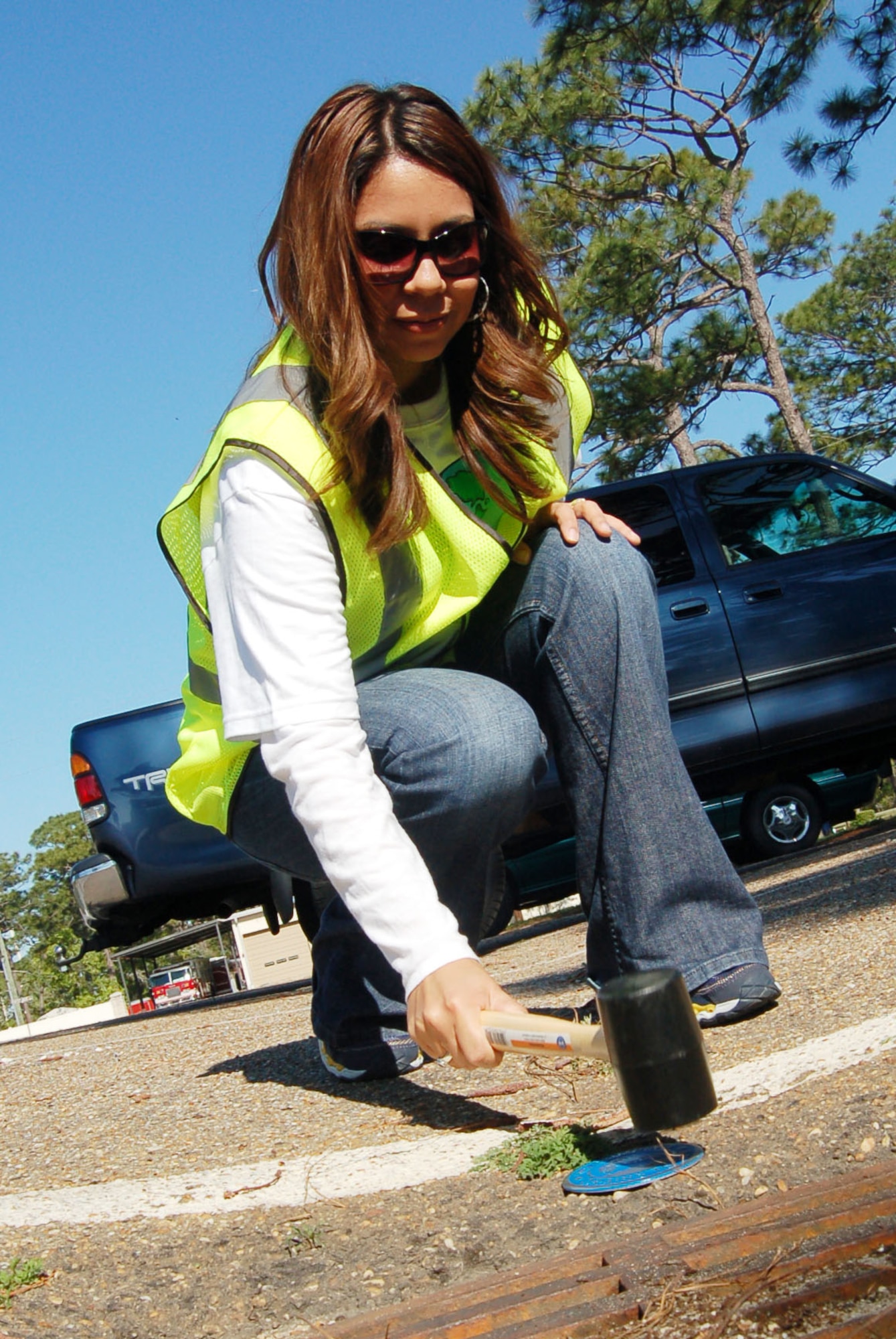Janice Dykas, 96th Civil Engineer Squadron environmental specialist, hammers a decal into place identifying a drain on Eglin AFB during Earth Day activities last year. Earth Day activities will occur throughout the week of April 16-23. Photo by Jerron Barnett. 