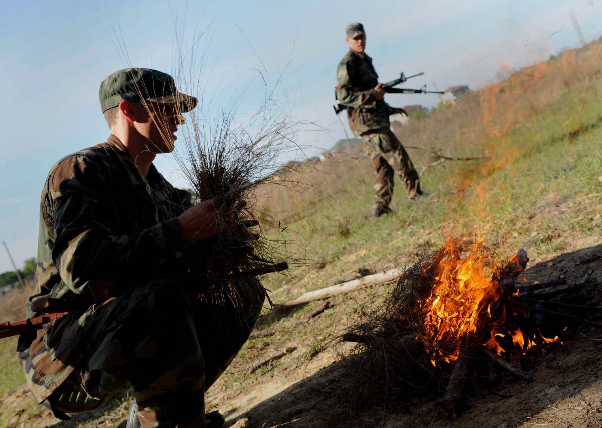 MOODY AIR FORCE BASE, Ga. -- A candidate from class 09A who is enrolled in the combat rescue officer selection course prepares to put brush onto a fire while another classmate collects sticks here March 25. The candidate's objective was to build a knee high maintainable fire. (U.S. Air Force photo by Senior Airman Gina Chiaverotti) 