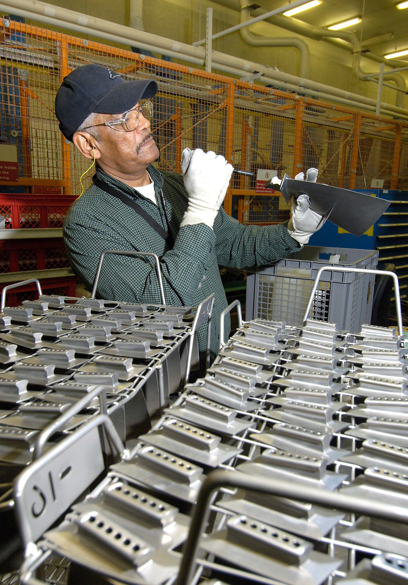 Terry Bruner uses a small flashlight to check holes of F110/100 fan blades, hunting for any media left over after the blades were shot peened. Shot peening uses various media, steel wire in this instance, to bombard specific reworked areas, strengthening the metal as it was before the rework. (Air Force photo/Margo Wright)
