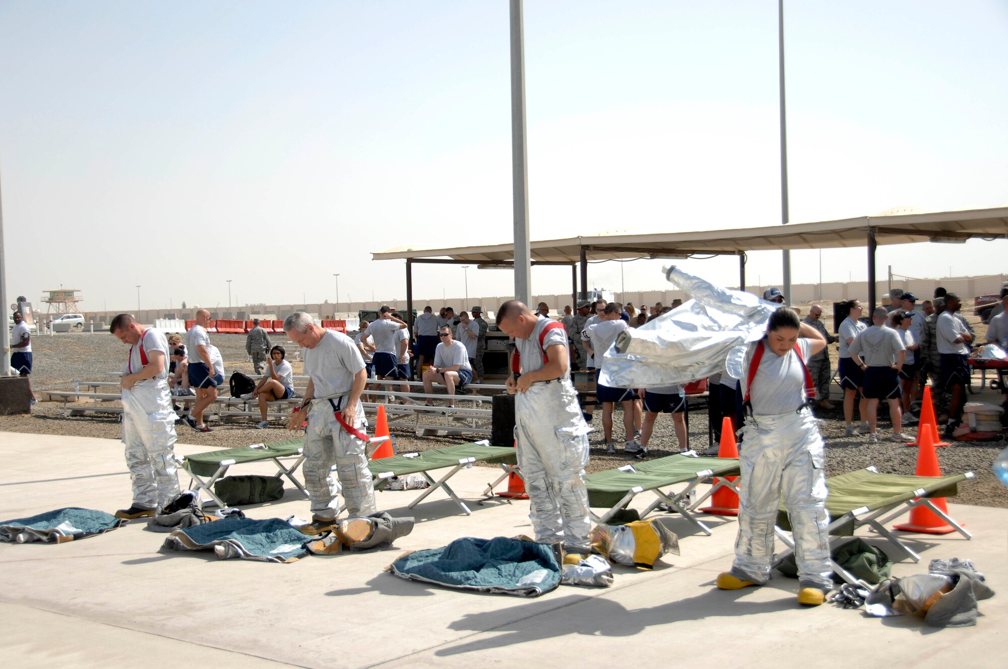 Members of the 380th Expeditionary Mission Support Group fire muster team don protective suits during the "midnight fire alarm" challenge of a fire muster challenge March 21 at an air base in Southwest Asia. A total of 56 Airmen made up 14 teams who competed in events such as a dummy carry, bucket brigade and fire hose roll-up. (U.S. Air Force photo/Staff Sgt. Mike Andriacco) 
