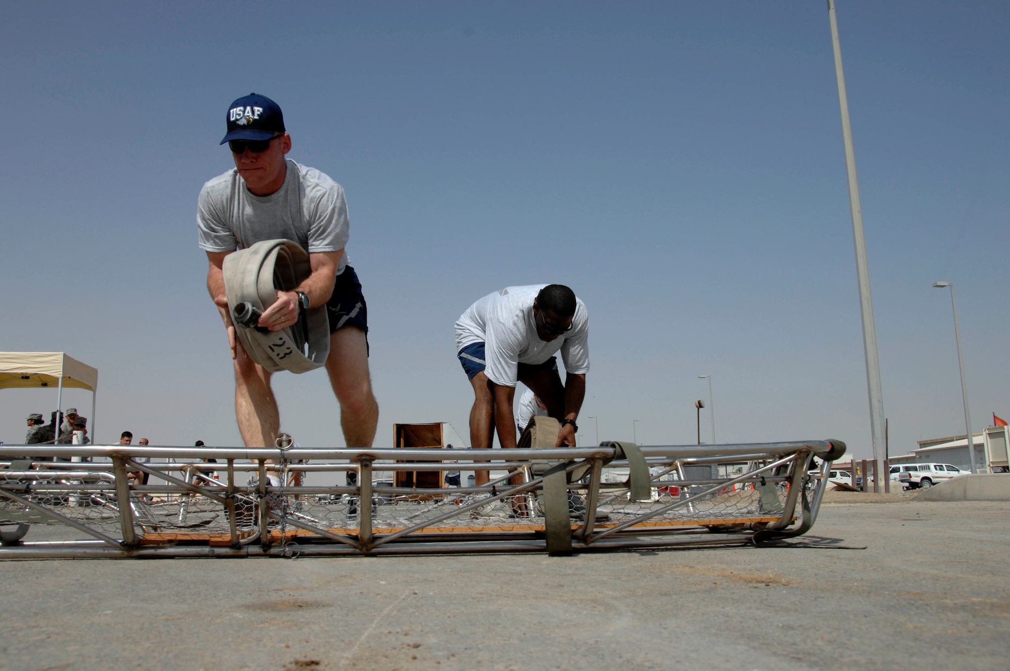 Lieutenant Col. Virgil Cole and Tech. Sgt. Curtis Cross place rolled up fire hoses onto a stretcher during a fire muster competition March 21 at an air base in Southwest Asia. Participants in the fire muster got a small taste of the training Air Force firefighters use to keep their skills sharp and save lives. Colonel Cole is from the from the 380th Air Expeditionary Wing Safety Office, and Sergeant Cross is assigned to the 380th AEW anti-terrorism office. (U.S. Air Force photo/Staff Sgt. Mike Andriacco) 
