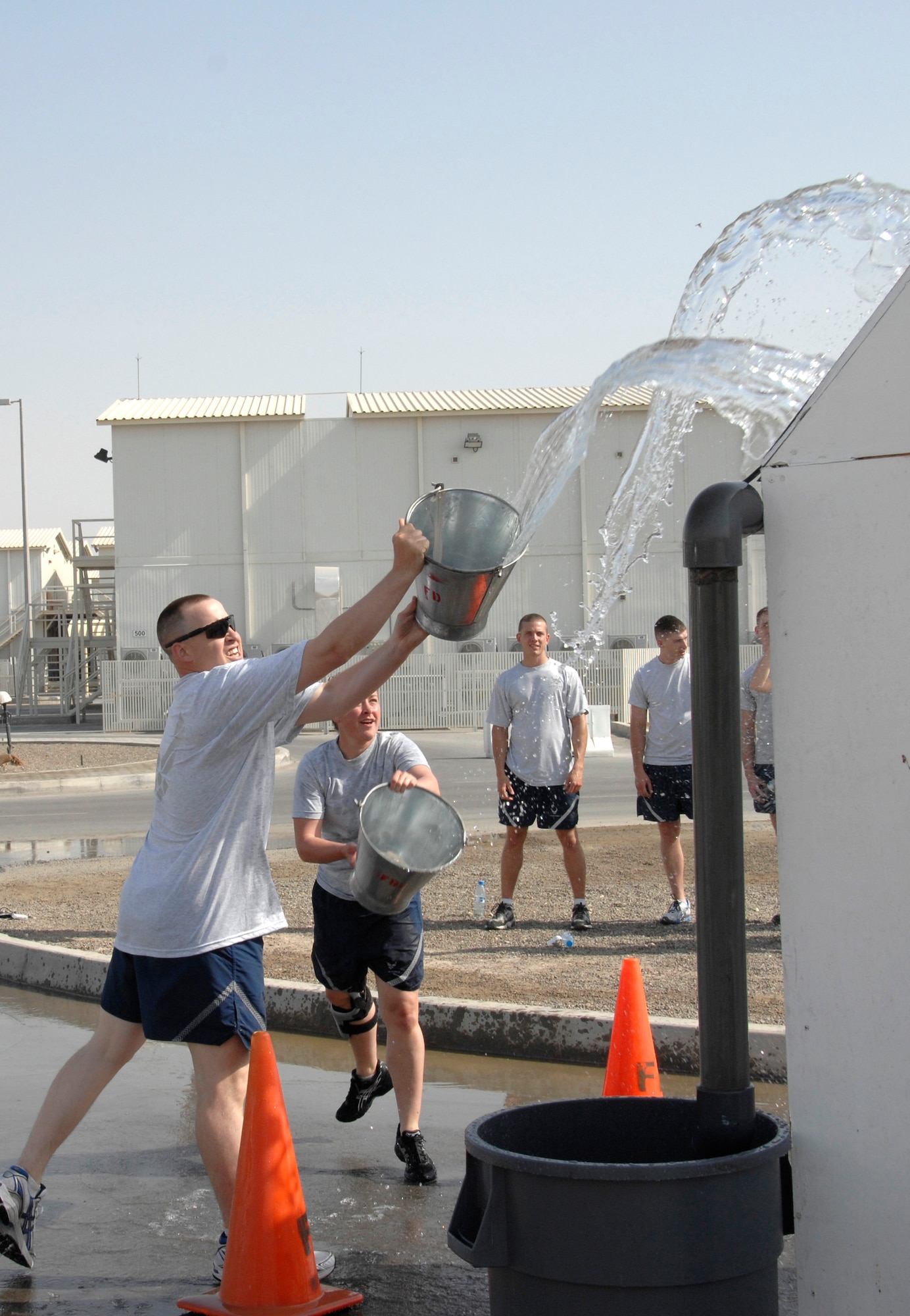 Technical Sgt. Lee Kvittem and Airman 1st Class Heather Bennett take part in the bucket brigade competition during a fire muster challenge March 21 at an air base in Southwest Asia. For this challenge, competitors had to throw buckets of water on a simulated roof, which would run down a gutter and fill a garbage can. Once the water reached the correct level, the challenge was complete and the team's time was recorded. Both were from the 380th Expeditionary Security Forces Squadron fire muster team. (U.S. Air Force photo/Staff Sgt. Mike Andriacco) 

