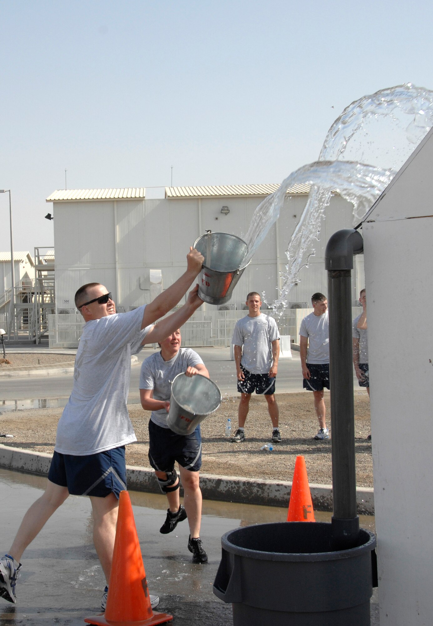SOUTHWEST ASIA -- Tech. Sgt. Lee Kvittem and Airman 1st Class Heather Bennett, both on the 380th Expeditionary Security Forces Squadron fire muster team, take part in the bucket brigade competititon during a fire muster challenge here March 21. For this challenge, competitors had to throw bukets of water on a simulated roof, which would run down a gutter and fill a garbage can. Once the water reached the correct level, the challenge was complete and the teams time was recorded. (U.S. Air Force photo by Staff Sgt. Mike Andriacco) (Released)