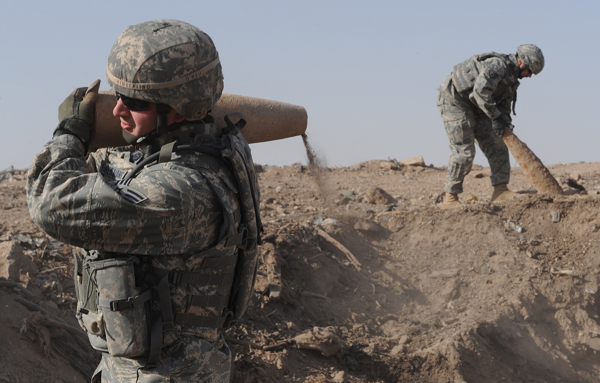 JOINT BASE BALAD, Iraq -- Senior Airman Mathew Kimberling, 332nd Expeditionary Civil Engineer Squadron explosive ordnance disposal journeyman, carries a 155-mm projectile as Staff Sgt. Christopher Adjoodani, 332nd ECES EOD craftsman, inspects another projectile here March 26. The EOD team here accepts and destroys unserviceable and damaged munitions in addition to responding to explosive hazards on and off base. Kimberling is deployed here from Travis Air Force Base, Calif., and is a native of Lincoln City, Ore. Adjoodani is deployed here from Dover AFB, Del., and is from Sacramento, Calif. (U.S. Air Force photo/Senior Airman Elizabeth Rissmiller)
