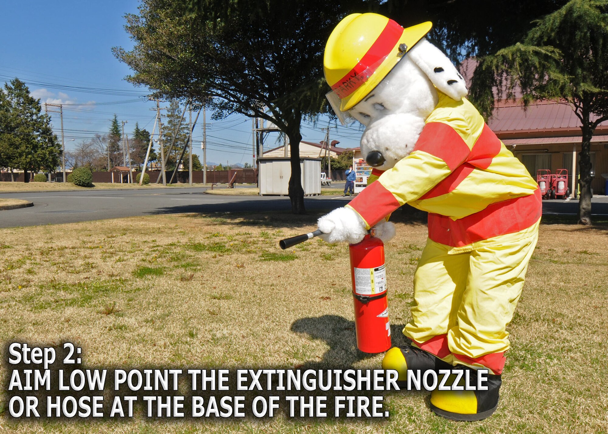 YOKOTA AIR BASE, Japan -- Sparky the Fire Dog demonstrates how to properly engage a fire extinguisher. The 374th Civil Engineer Squadron fire department is promoting spring fire prevention week April 13 through 17. (U.S. Air Force illustration/ Senior Airman Veronica Pierce)