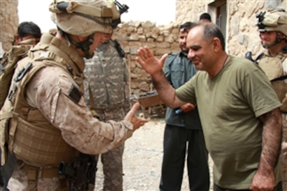 U.S. Marine Corps Lt. Col. David L. Odom, commanding officer, 3rd Battalion, 8th Marine Regiment, and Afghan National Police chief Col. Abdul Qadoss, commander of the Delaram district in Farah, Afghanistan, greet each other, March 23, 2009, in Delaram. Odom and Qadoss discussed increased security measures and the bravery recently displayed by the Afghan National Police during an attack by a vehicle-borne explosive device. 