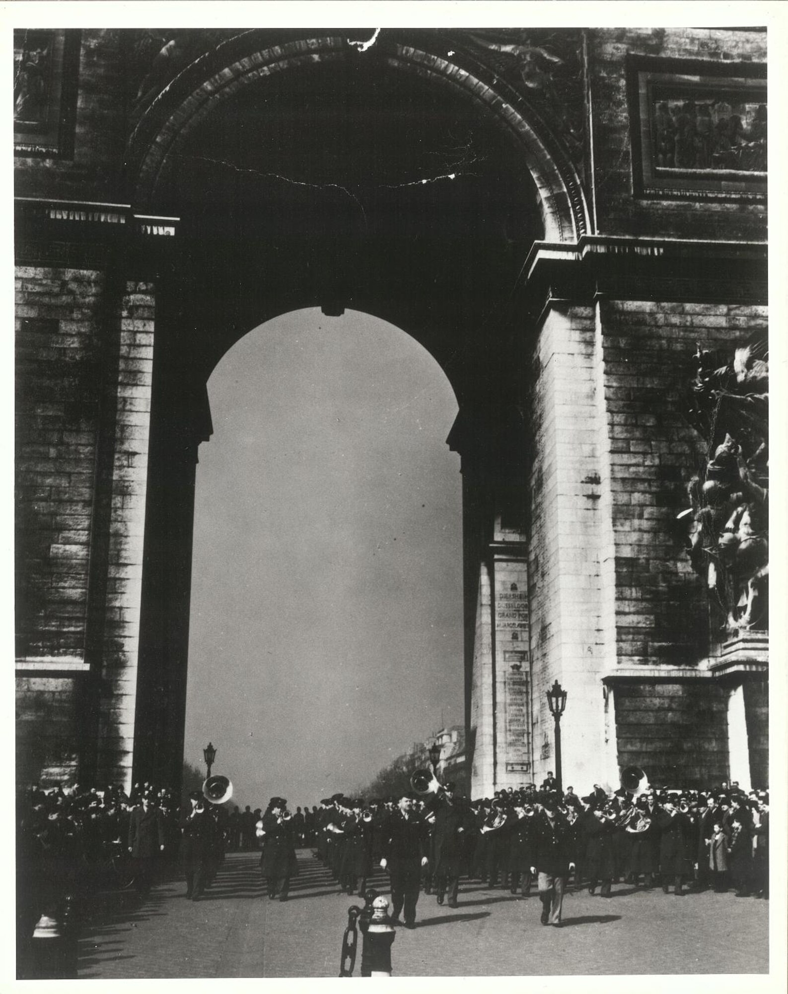 In 1944, General Henry "Hap" Arnold organized an Anglo American Lend-Lease program which called for an exchange of bands between the United States Air Force and the Royal Air Force.  The Army Air Forces Band's left Bolling Field on December 5, 1944 and returned on April 5, 1945.  This photo was taken on March 15, 1945 at the Arc de Triomphe in Paris, France.  According to Master Sgt. (USAF, Ret.) Ivan Genuchi's detailed scrapbook from that tour, this was a posed photo, i.e. no parade and no concert (much to the disappointment of the civilian population).  After the Band returned from this photo op, several were treated to a performance that evening by the Glenn Miller Army Air Forces Band in the hotel dining room in Paris and again during the Miller Band's 10 p.m. recording session.