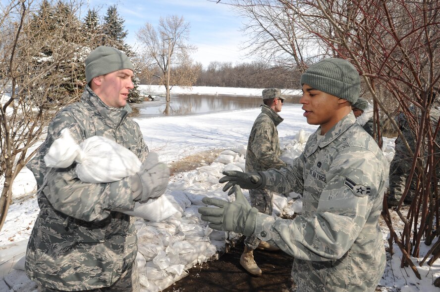 Senior Airman Timothy Stencil and Airman 1st Class Karlon Johnson  were two Warriors of the North tasked to save 69 homes located in south Grand Forks along the Red River March 28. Approximately 80 Airmen joined residents and other community volunteers to form a line to pass sandbags to increase dike height to 54 feet. (U.S. Air Force photo/Tech. Sgt. Johnny L. Saldivar)