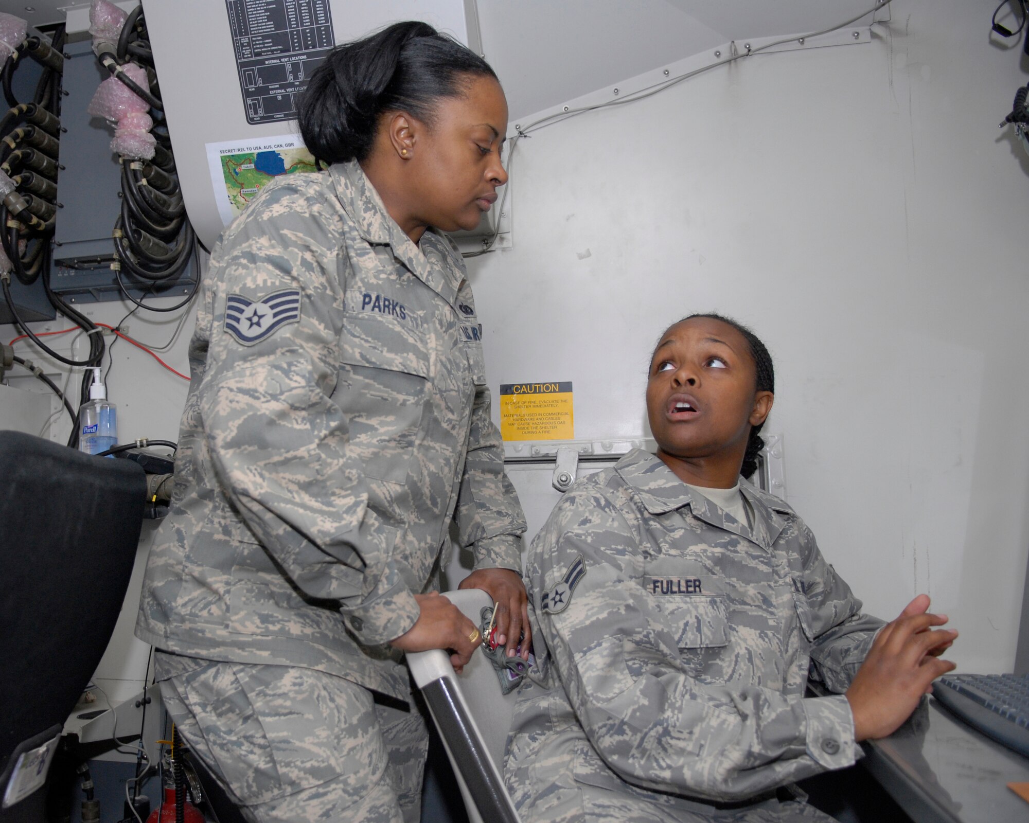 Staff Sgt. Kim Parks listens to her daughter, Airman 1st Class Monique Fuller, explain her job as a datalink specialist with the 71st Expeditionary Air Control Squadron March 13, 2009. Sergeant Parks is a postal aerial mail terminal chief here.  (U.S. Air Force photo by Senior Airman Andrew Satran)
