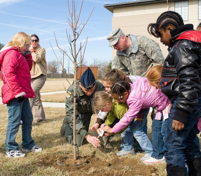 (Middle) Col. Eric Wydra, 436th Airlift Wing vice commander, and (Right) Chief Master Sgt. John Wood, 436th AW command chief, along with children from the youth center help plant a Silver Maple tree March 24 in honor of Women's History Month. (U.S. Air Force photo/Tom Randle)