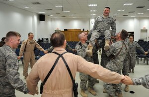 JOINT BASE BALAD, Iraq -- Tech. Sgt. Craig Lifton, 332nd AEW Public Affairs NCO-in-charge of journalism, laughs as he is hoisted up in the air by fellow servicemembers during his bar mitzvah here March 21 at Gilbert Memorial Chapel. The bar mitzvah took place after a dedication ceremony here celebrating the arrival of a Jewish Torah. A bar mitzvah is a rite of passage held traditionally for Jewish boys when they reach 13 years old and a day. Bar mitzvah literally means, "son of the commandment," -- meaning the person is now of age to fully participate in all aspects of the Jewish religion. (U.S. Air Force photo/Senior Airman Elizabeth Rissmiller)