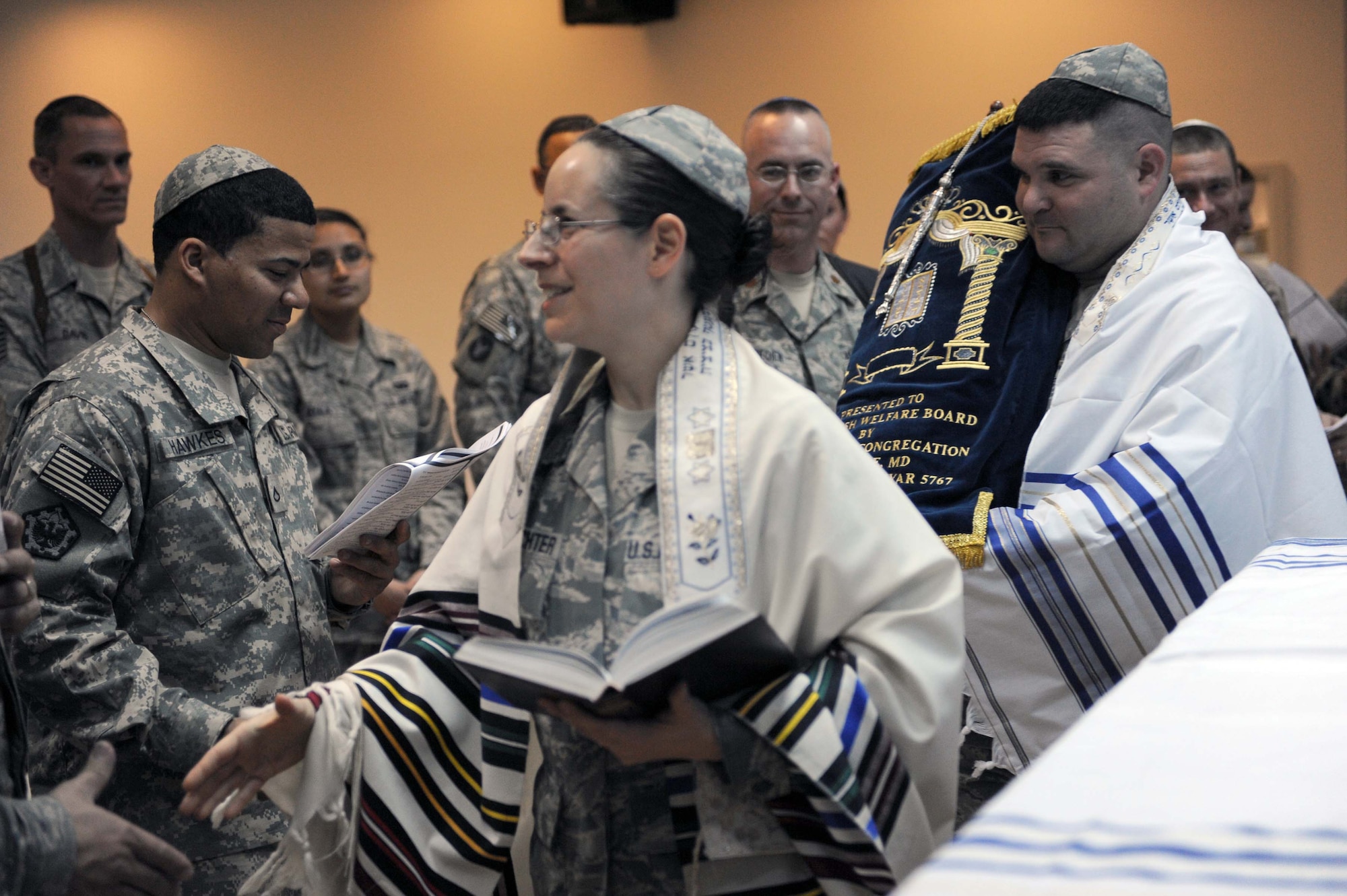 JOINT BASE BALAD, Iraq -- Chaplain (Capt.) Sarah Schechter, 332nd Air Expeditionary Wing rabbi, walks around and thanks servicemembers for attending the Torah dedication ceremony at Gilbert Memorial Chapel here March 21, while Tech. Sgt. Craig Lifton, 332nd AEW Public Affairs NCO-in-charge of journalism, carries the newly arrived Jewish Torah behind her. A Torah is a big parchment leather scroll on which the Five Books of Moses are handwritten in Hebrew. For thousands of years, this is how Jews have maintained their law, teachings, religion and society. (U.S. Air Force photo/Senior Airman Elizabeth Rissmiller)