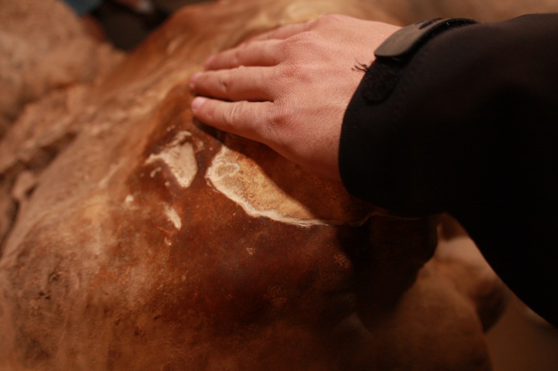 Lance Cpl. Aaron Kristopik, a paralegal with the Combat Center’s Staff Judge Advocate, reaches out and touches the wishing stone. The stone has been touched by thousands of visitors since the beginning of the tours, eroding it and giving it a somewhat glassy look.