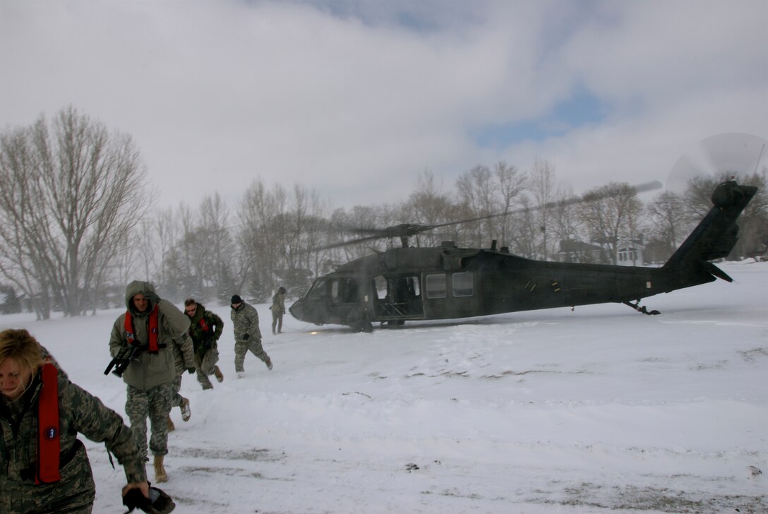 Ducking in the blowing snow from a UH-60 Blackhawk helicopters blades, members of the Minnesota National Guard disembark after a survey flight over the Red River in Moorhead Minnesota during the flood of 2009.
U.S. Air Force Photo by Tech Sgt Erik Gudmundson 
