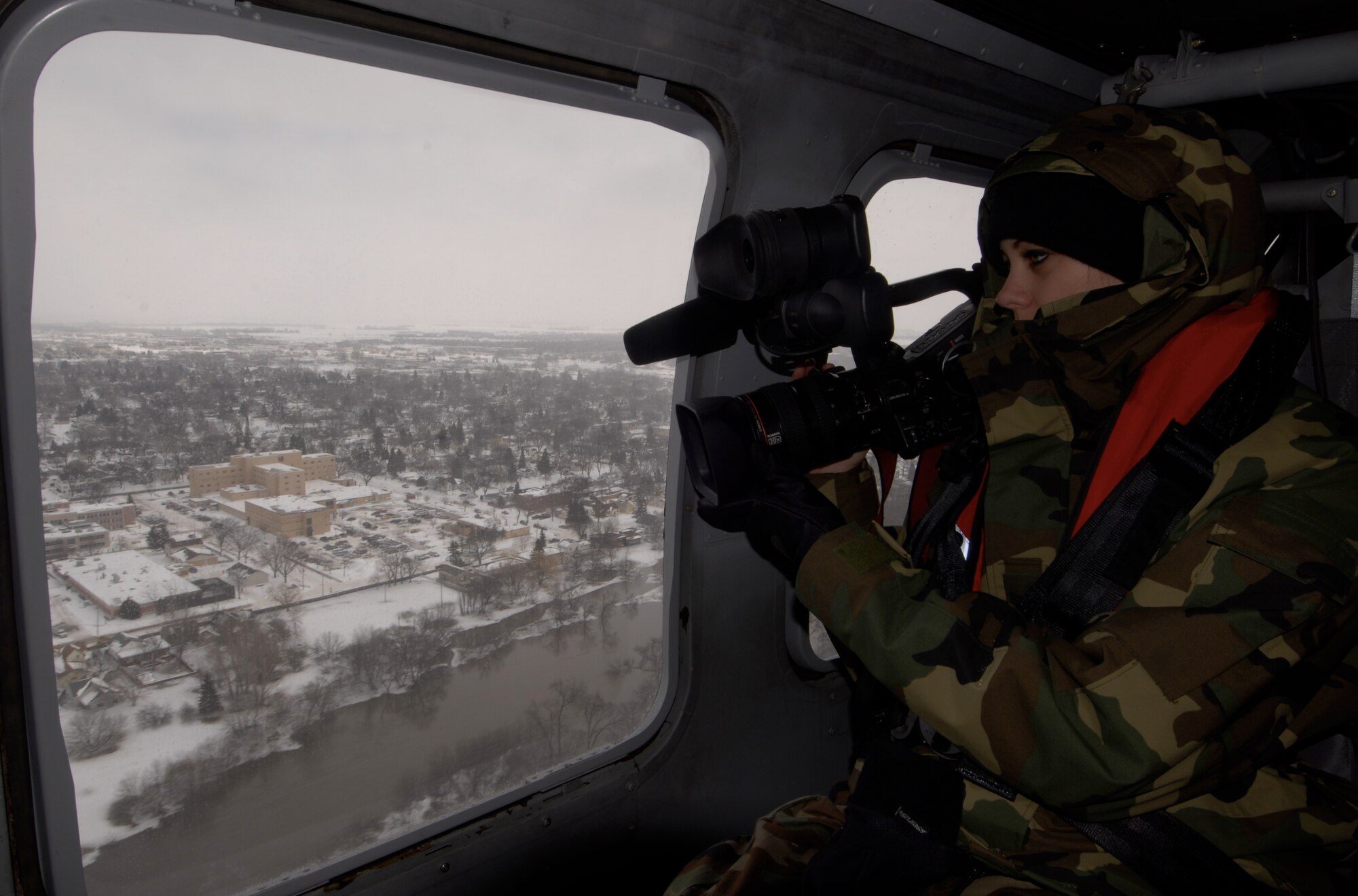 Staff Sgt. Amber Monio, a broadcast journalist with the 133rd Airlift Wing Public Affairs, Minnesota Air National Guard captures video of the record setting flooding from the window of a UH-60 Blackhawk over Moorhead, Minnesota. Staff Sgt. Monio is deployed to cover the support the Minnesota Guard is providing during the flood of 2009.
U.S. Air Force Photo by Tech Sgt Erik Gudmundson 
