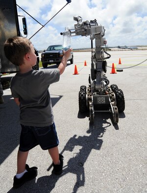 Dylan Hart is shown how the functions of a F6-Alpha Explosive Ordnance Robot work at Andersen Air Force Base, Guam, Open House Mar. 28. The explosive ordnance disposal unit also featured the EOD-9 bombsuit and the new chemical warfare suit. (U.S. Air Force photo/Airman 1st Class Courtney Witt) 