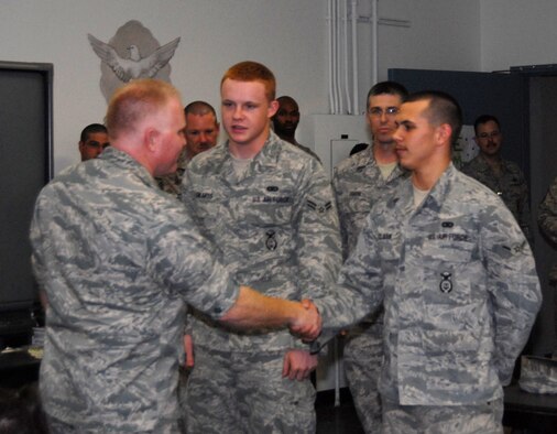 Col. Jerry Gandy (left), 95th Air Base Wing commander, coins Airman 1st Class Joseph Edwards (middle) and Airman Justin Clark, both with 95th Security Forces Squadron during a welcome home reception March 13. Airmen Edwards and Clark were the youngest deployers among the returning 95th SFS Airmen. (U.S. Air Force photo/Lisa Camplin)