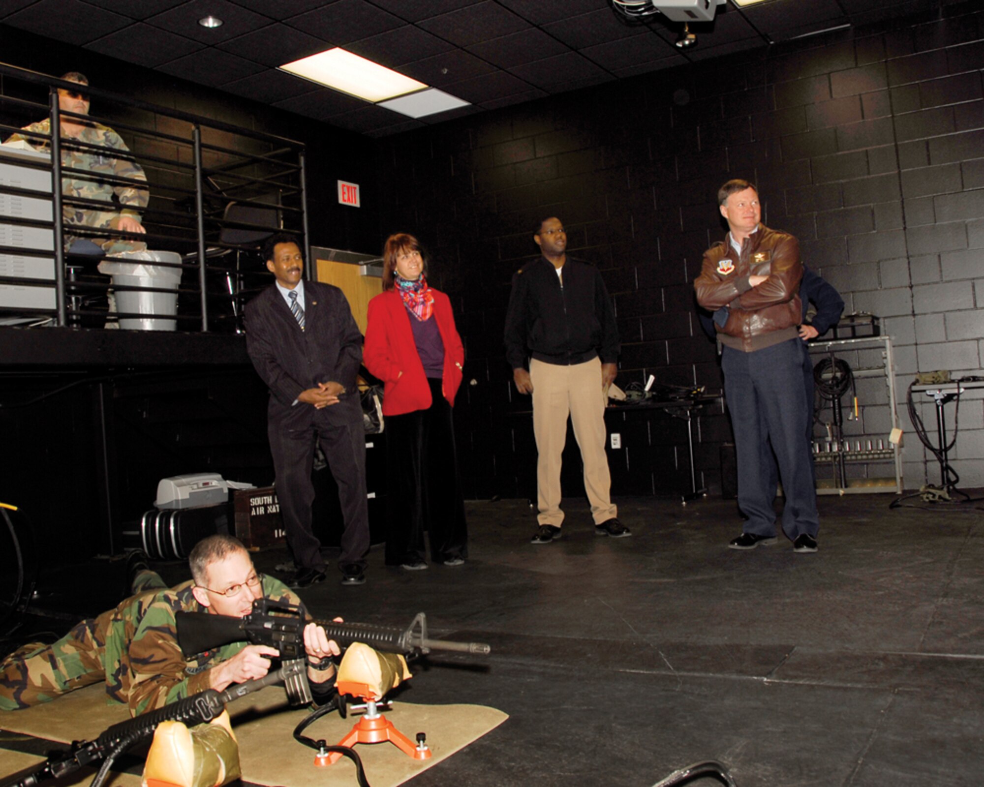 Capt. Joe Hardin, 114th Security Forces commander, demonstrates his marksmanship skills in the Firearms Training Simulator room during a tour by Suriname Defense Minister Ivan Fernald and U.S. Ambassador Lisa Bobbie Schreiber Hughes. Defense Minister Fernald and Ambassador Schreiber Hughes were in South Dakota for a tour of the state as part of the Growth through Partnership program.