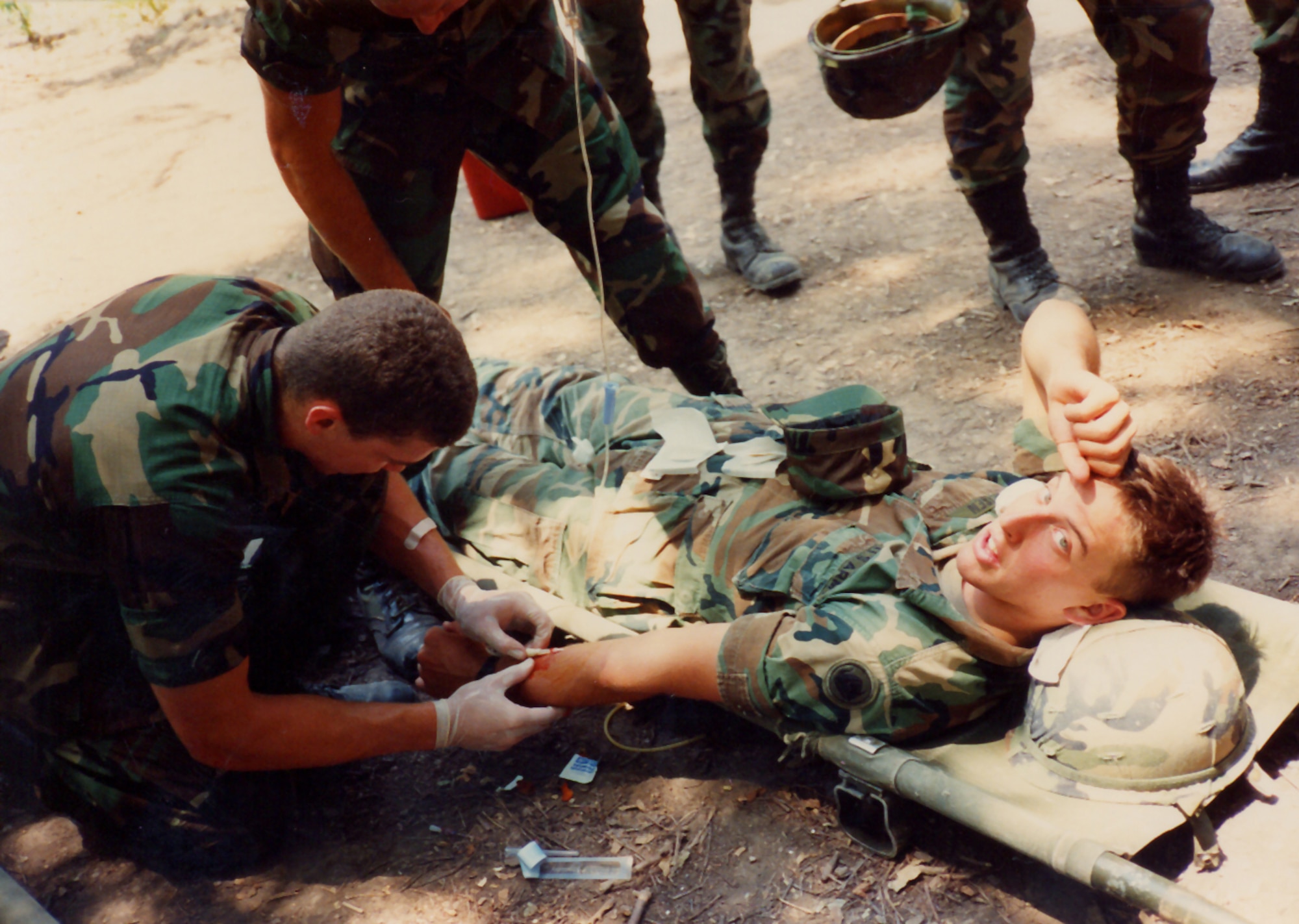 A battle buddy administers an IV into Private Geisen's arm during monthly field training during the summer of 1989 at Fort Sam Houston, Texas. Private Geisen later became an Army officer, and then joined the Navy and Air Force. Major Geisen is now a 40th Helicopter Squadron pilot. (Courtesy photo)