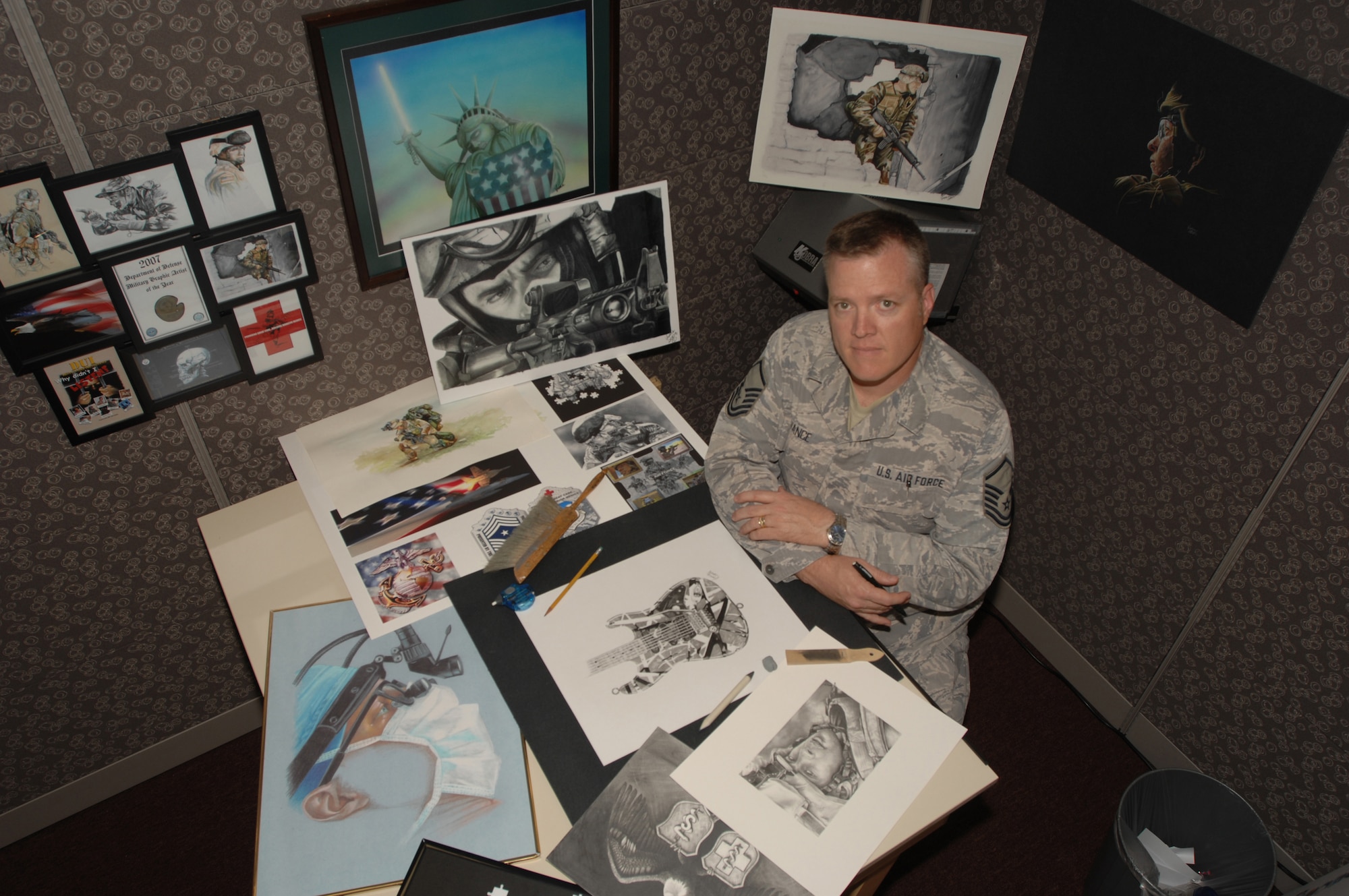 Master Sgt. William "Cody" Vance sits surrounded by his art, much of it award-winning.  Sergeant Vance, assigned to the 59th Medical Wing Medical Multimedia Center, is the recipient of the 2008 Military Graphic Artist of the Year for the second time in a row.  He is the last Senior Noncommissioned Officer in the Air Force's graphic arts career field. (U.S. Air Force photo/Senior Airman Robert Barnett)