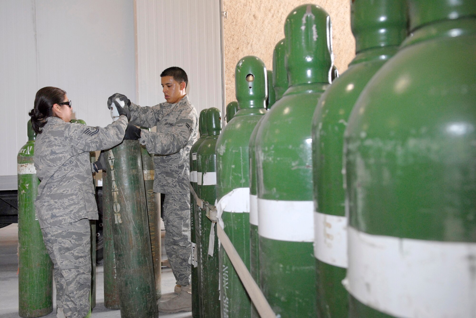 Tech. Sgt. Rebecca Gonzales, 379th Expeditionary Logistics Readiness Squadron (ELRS) NCO in charge Hazmat Pharmacy and Airman 1st Class Christopher Ramos, a 379th ELRS hazmat pharmacy journeyman, unload a shipment of oxygen tanks to be distributed throughout the base and the U.S. Central Command's Area of Responsibility, Mar. 29, 2009, at an undisclosed location in Southwest Asia.  The Hazmat Pharmacy is responsible for liquid oxygen, nitrogen, corrosive liquids, flammables, and other chemicals used by forces throughout the U.S. Central Command's Area of Responsibility.  Sergeant Gonzales hails from San Antonio, Texas and is deployed from the 149th Air National Guard Base Lackland, Texas.  Airman Ramos hails from Orange County, Calif. and is deployed from Altus Air Force, Okla.  Both are deployed in support of Operations Iraqi and Enduring Freedom and Combined Joint Task Force - Horn of Africa.  (U.S. Air Force photo/Senior Airman Andrew Satran/released)    