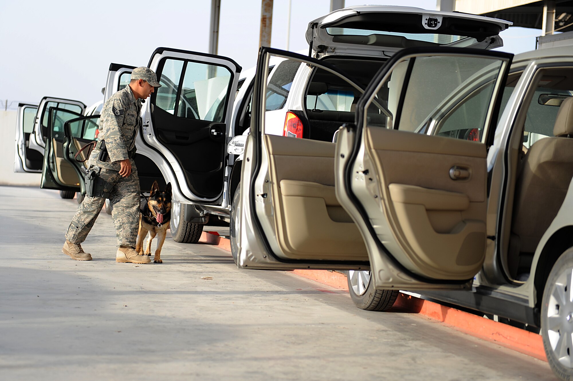 SOUTHWEST ASIA - Staff Sgt. Estanislao Rodriguez, 380th Expeditionary Security Forces Squadron, military working dog handler and his dog Kira inspect incoming vehicles in the vehicle search area, Mar 21. The VSA is responsible for ensuring all vehicles coming from off base locations are safe and free of contraband before entering back onto the base. Sergeant Rodriguez and Kira are deployed from the 12th Security Forces Squadron, Randolph AFB, Texas. Sergeant Rodriguez hails from Buda, Texas. (U.S. Air Force photo by Senior Airman Brian J. Ellis) (Released)