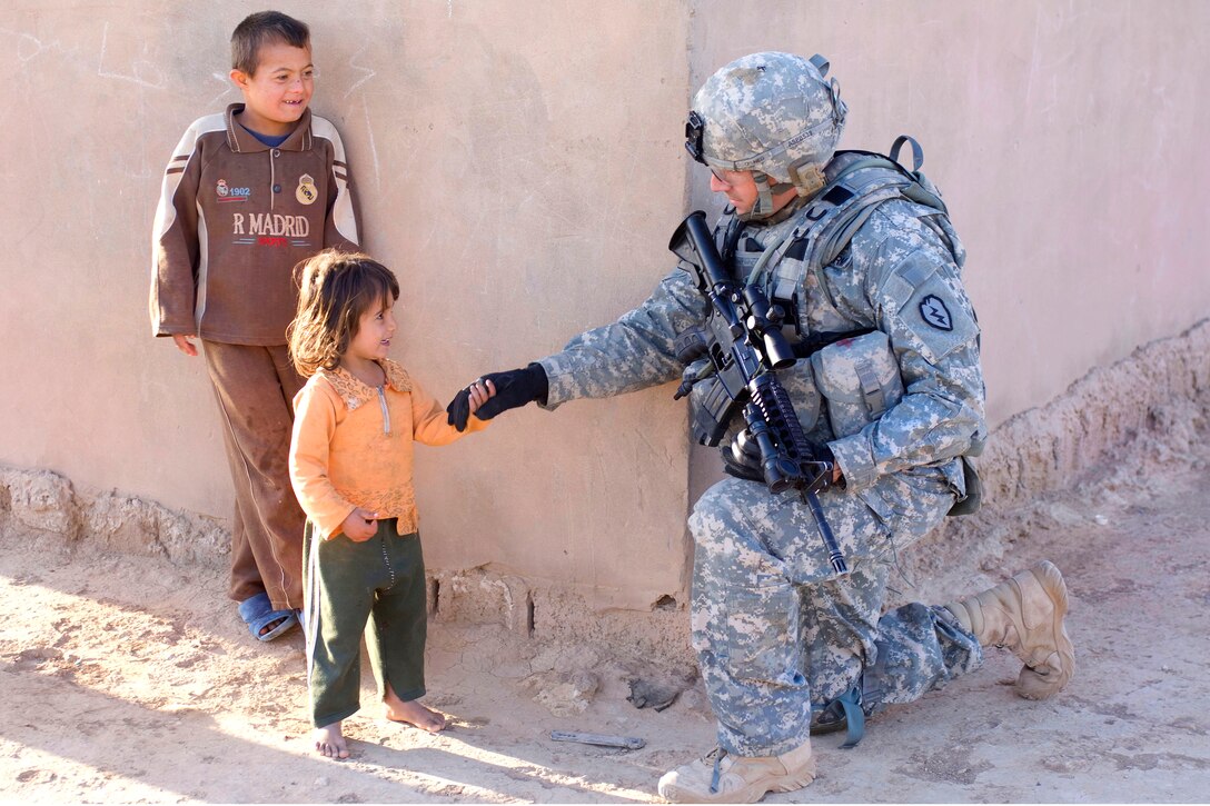 Iraqi children greet U.S. Army Spc. Jeremy Sparks during a clearing operation in Shuzayf, Iraq, March 26, 2009.