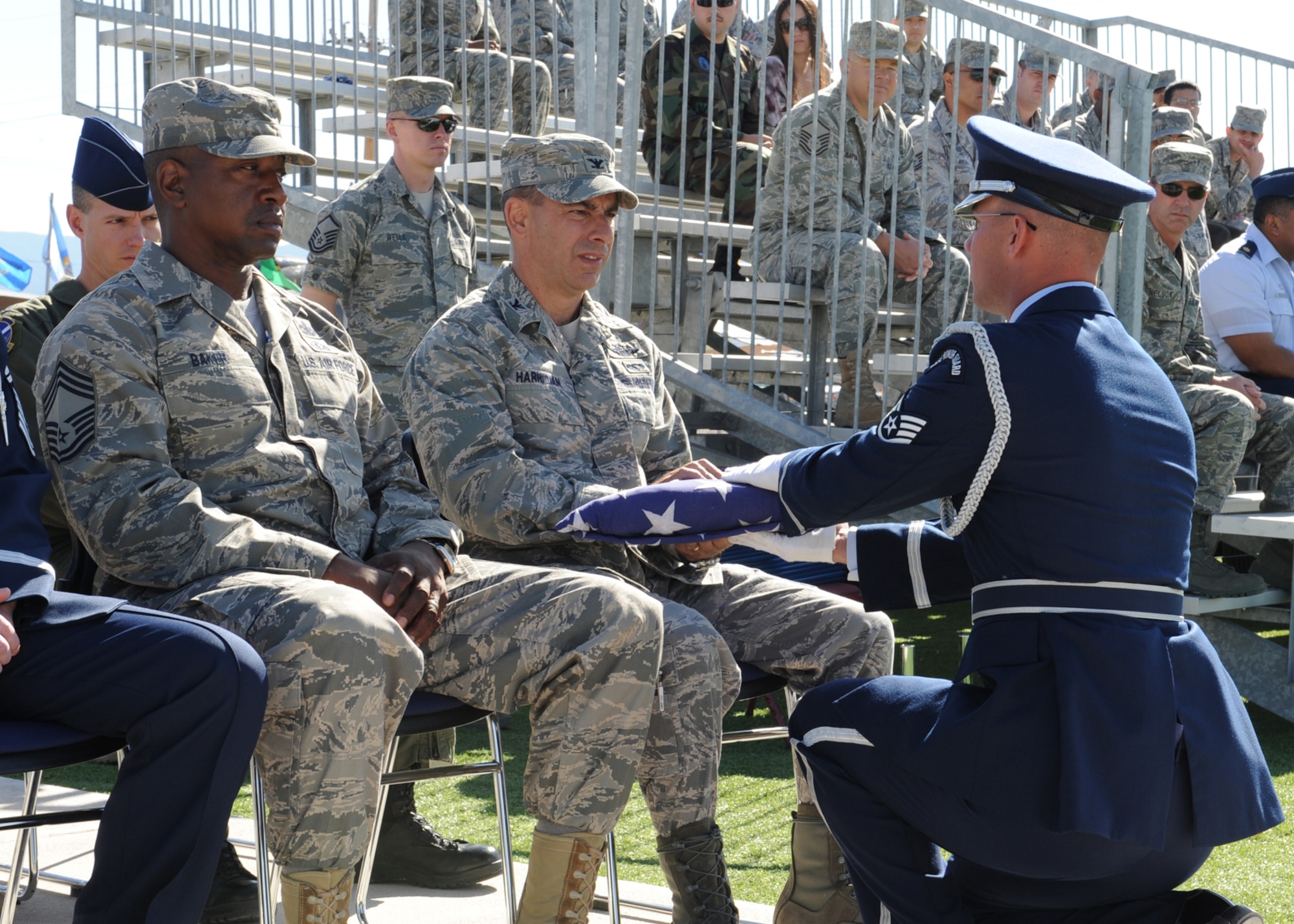 A member of the Holloman Air Force Base Honor Guard presents Col. Jeff Harrigian, 49th Fighter Wing commander, with the U.S. Flag during a graduation ceremony recognizing members of the base honor guard team March 25. The honor guard completed a week long training course instructed by members of the Air Force Honor Guard. 