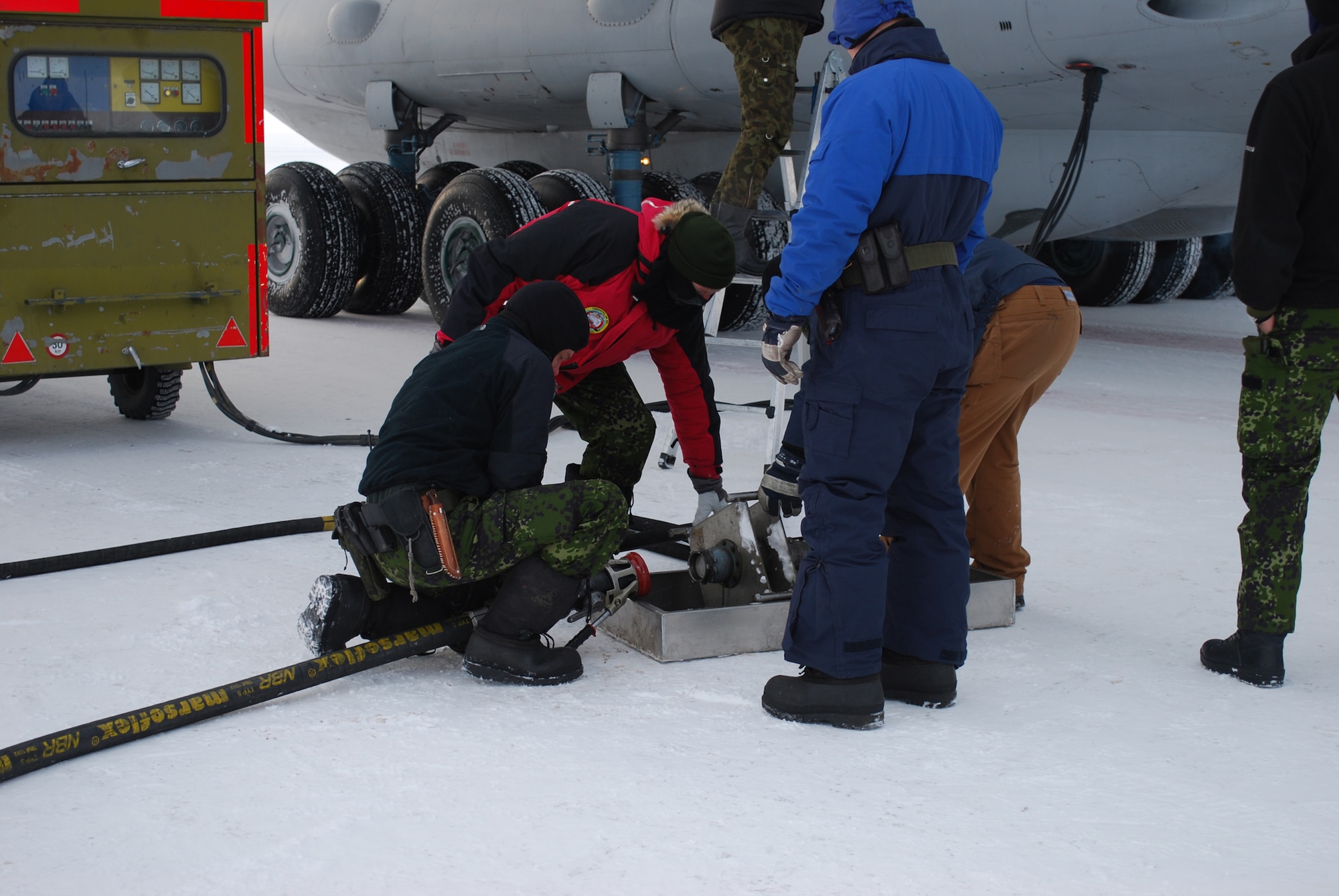 Ukrainians and Danes transfer fuel from a Ukrainian IL-76 Ilyushin aircraft to reserve tanks at the Danish military outpost, Station Nord, some 600 miles north of Thule Air Base, Greenland, March 23 during Operation Brilliant Ice 2009.  The fuel delivery, supplied by Ukraine strategic airlift, will sustain Station Nord for another year. (U.S. Air Force photo/1st Lt. Lisa Meiman). 
