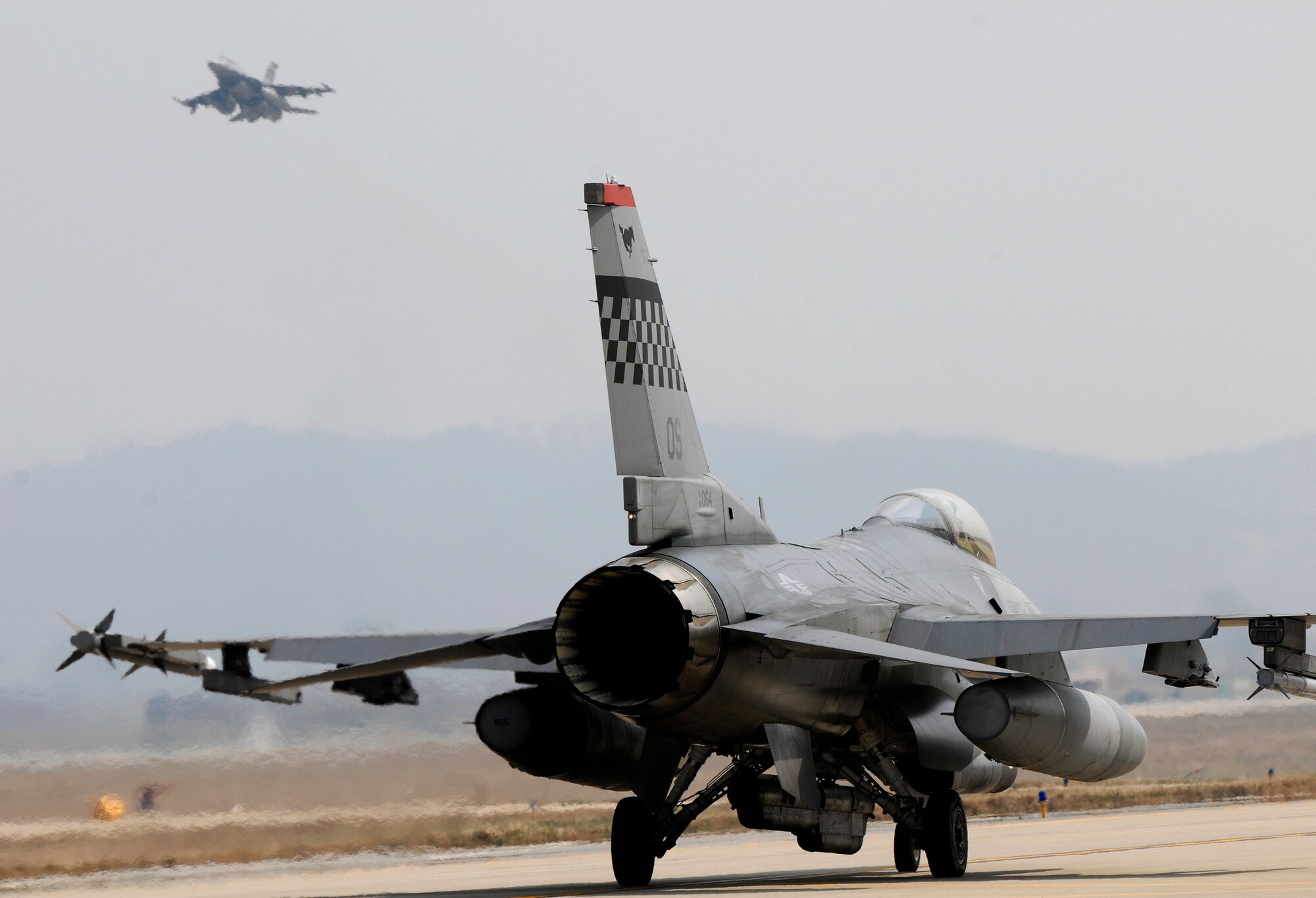 An F-16 Falcon taxis down the tarmac as another Falcon lifts off at Osan Air Base, Republic of Korea, during Operations Readiness Exercise Beverly Bulldog 09-02, March 31. The pre-scheduled exercise is designed to help the 51st Fighter Wing prepare for their Operational Readiness Inspection in April. (U.S. Air Force photo/Staff Sgt. Brian Ferguson)