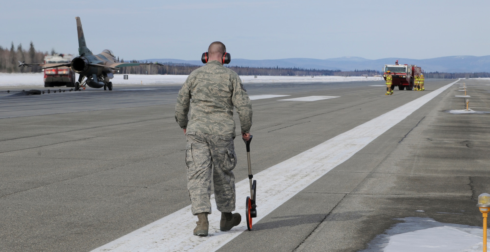 Tech. Sgt.  Dale Wilson uses a measuring wheel March 25, 2009, Eielson Air Force Base, Alaska. Sergeant Wilson measures 853-feet as the total distance it took for the arresting break cable to stop the F-16 Fighting Falcon. Sergeant Wilson is the 354th Operations Support Squadron NCO in charge for Airfield Management Operations. (U.S. Air Force photo/Airman 1st Class Laura Max)