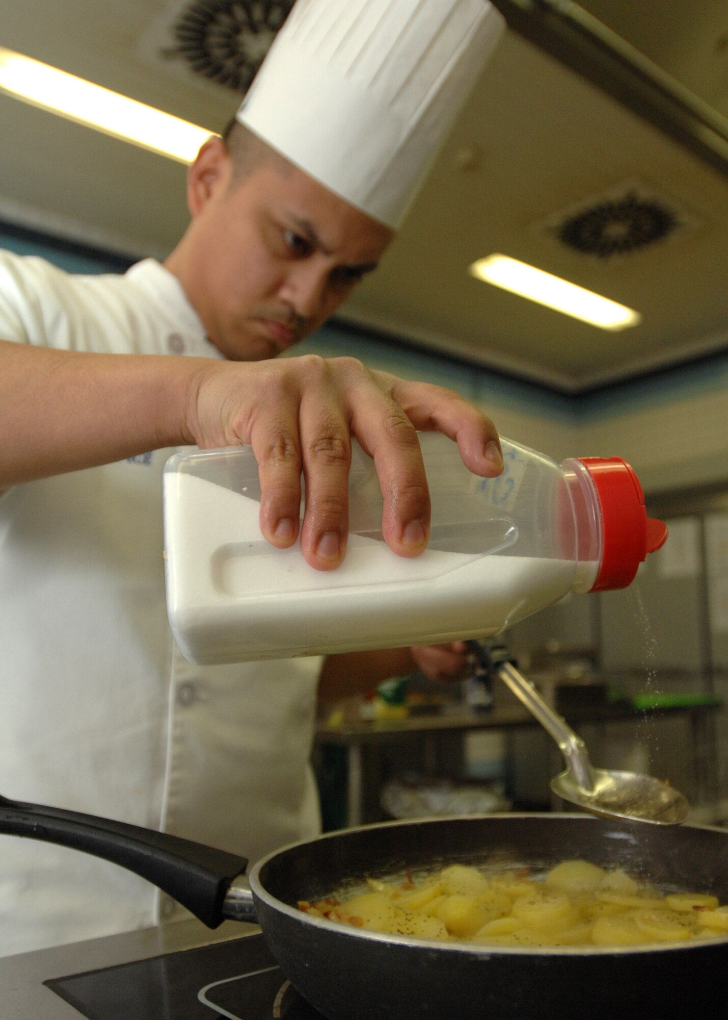 SPANGDAHLEM AIR BASE, Germany -- Tech. Sgt. Rommel Ongaco, 702nd Munitions Maintenance Squadron Team Beuchel, pours salt on potatoes March 30, 2009 during the Iron Chef competition at the Mosel Dining Facility.  Team Buechel won the title of Iron Chef after creating a winning combination of chicken cordon bleu, orange rice with crispy beef and mushroom stuffed chicken. (U.S. Air Force photo by Senior Airman Jenifer H. Calhoun)